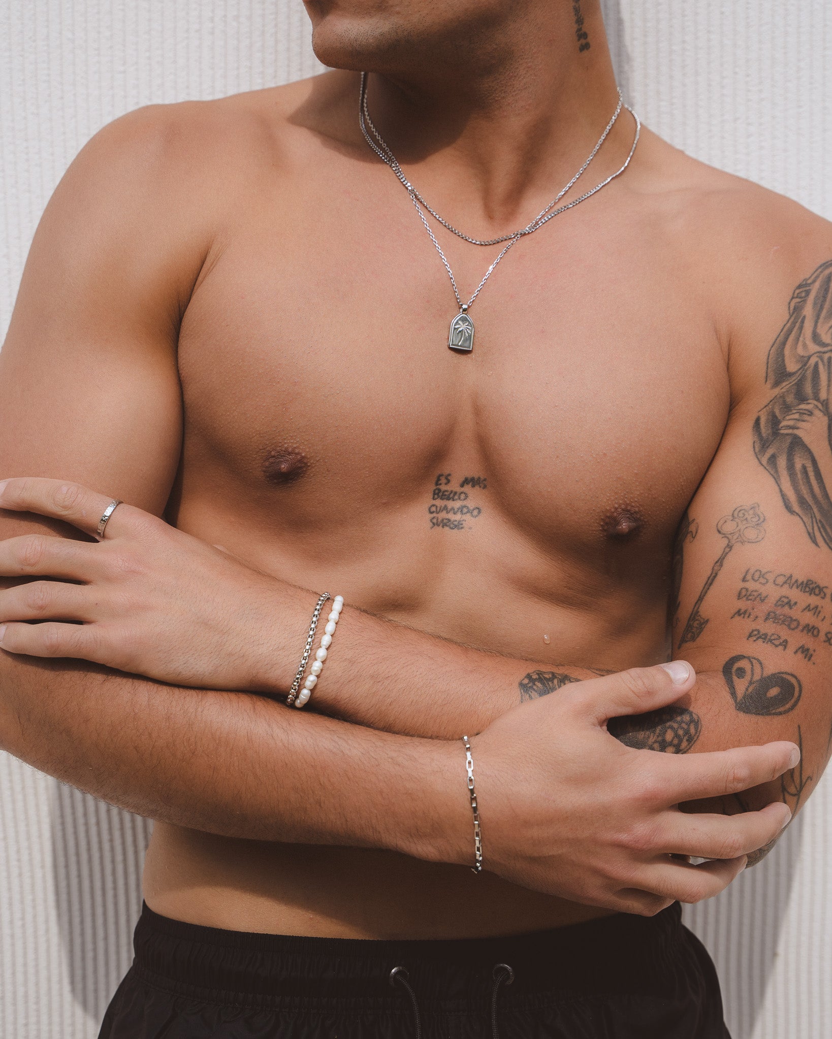 Belize Pearl Bracelet worn on a man's wrist featuring Caribbean freshwater pearls and layered silver necklaces