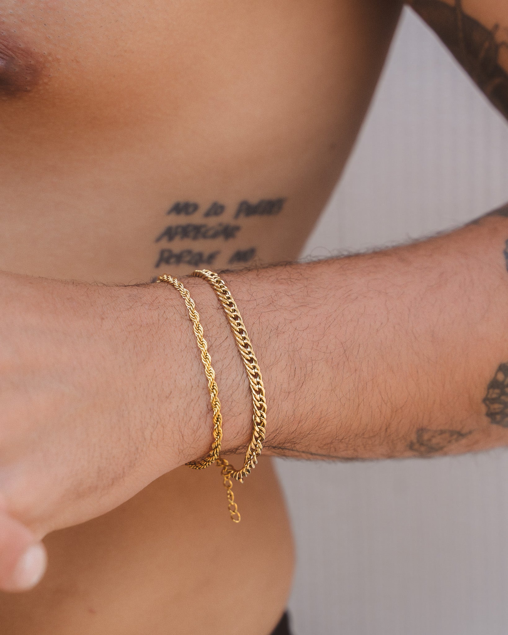 Two Coral Gold rope chain bracelets stacked on a tattooed forearm