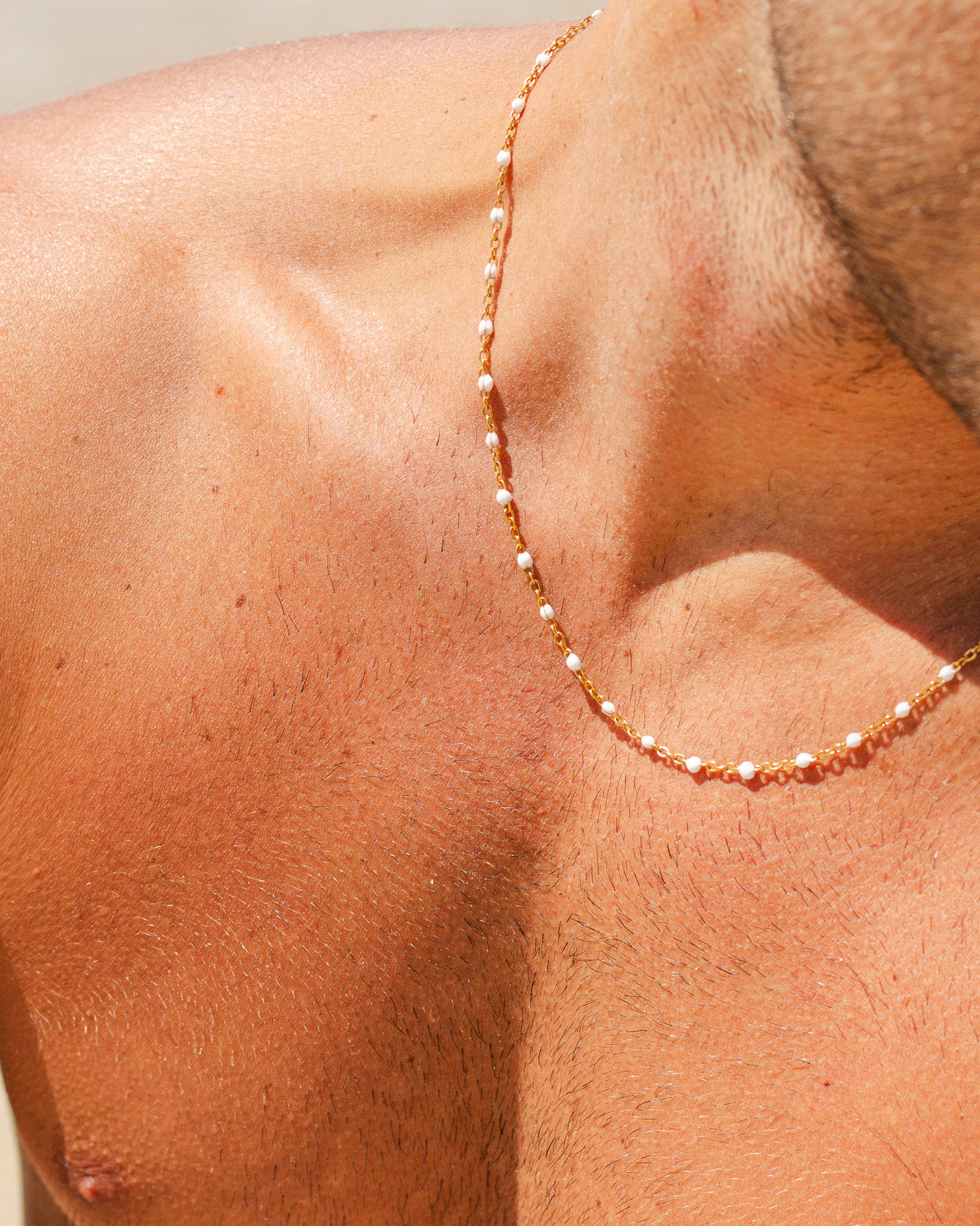 Delicate GEM GOLD CHAIN with white beads draped along the shoulder on sunlit skin