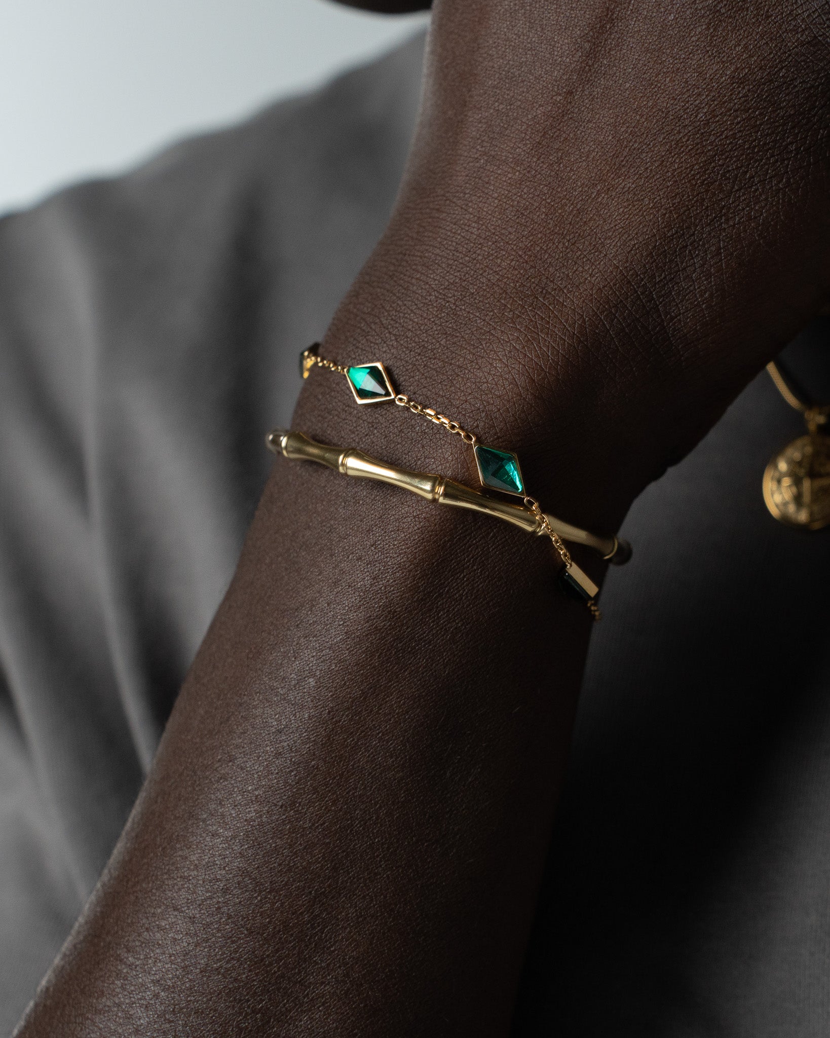 Amberes gold bracelet with green square gemstones worn on a dark-skinned wrist