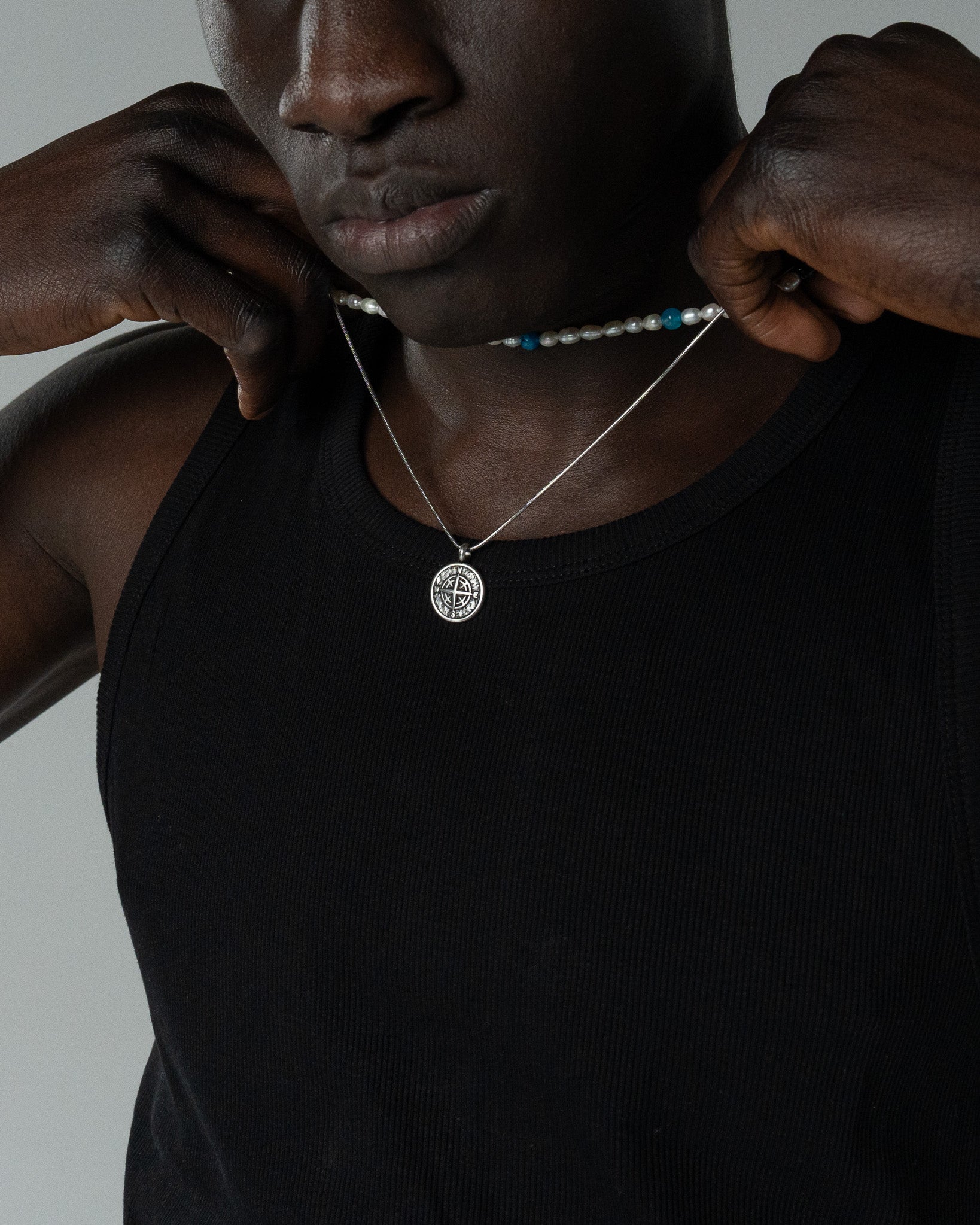 Close-up of MOJAVE compass pendant necklace resting on the chest against a black shirt