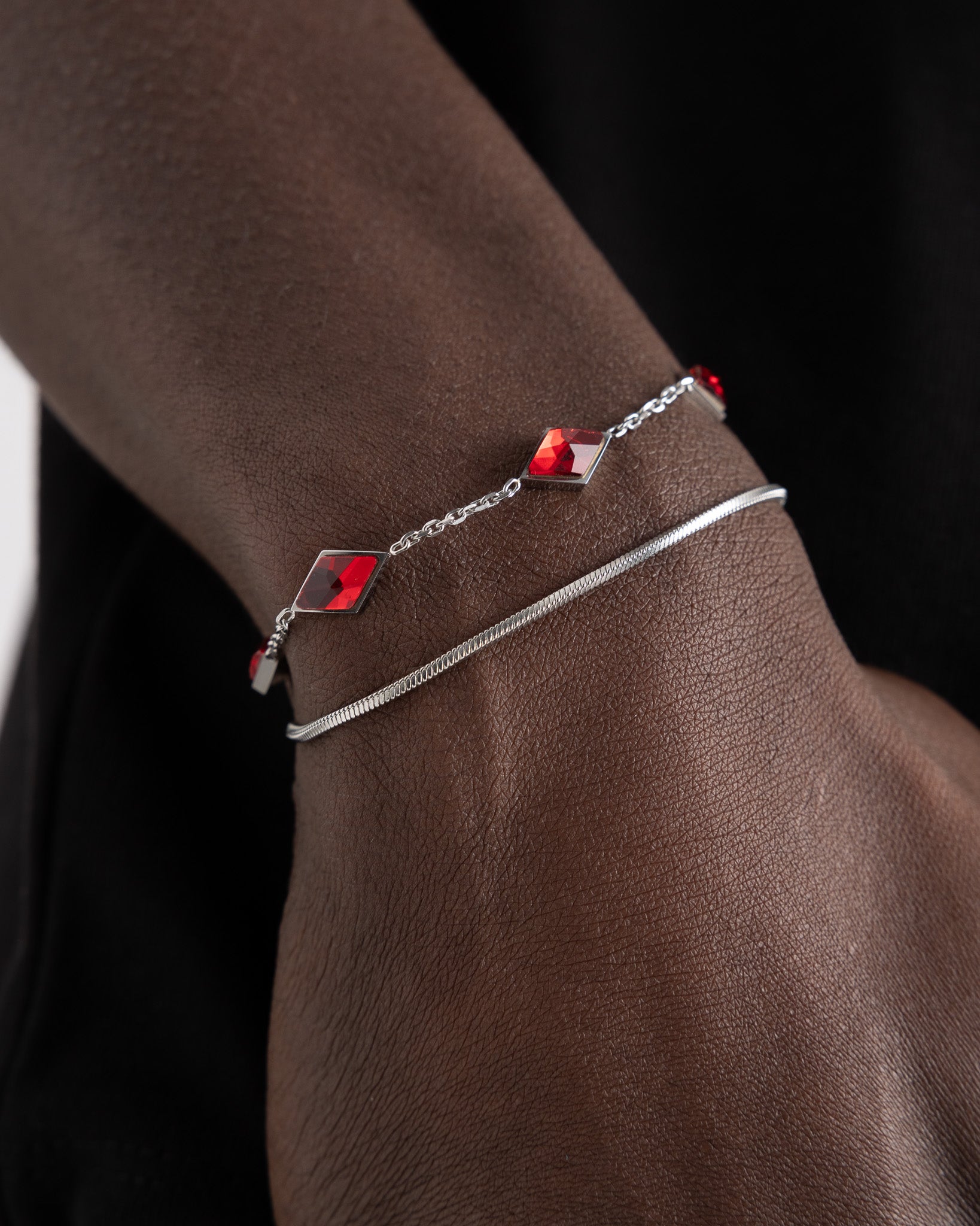 Close up of Amberes silver bracelet on the wrist showing a red square gemstone and the metal chain clasp