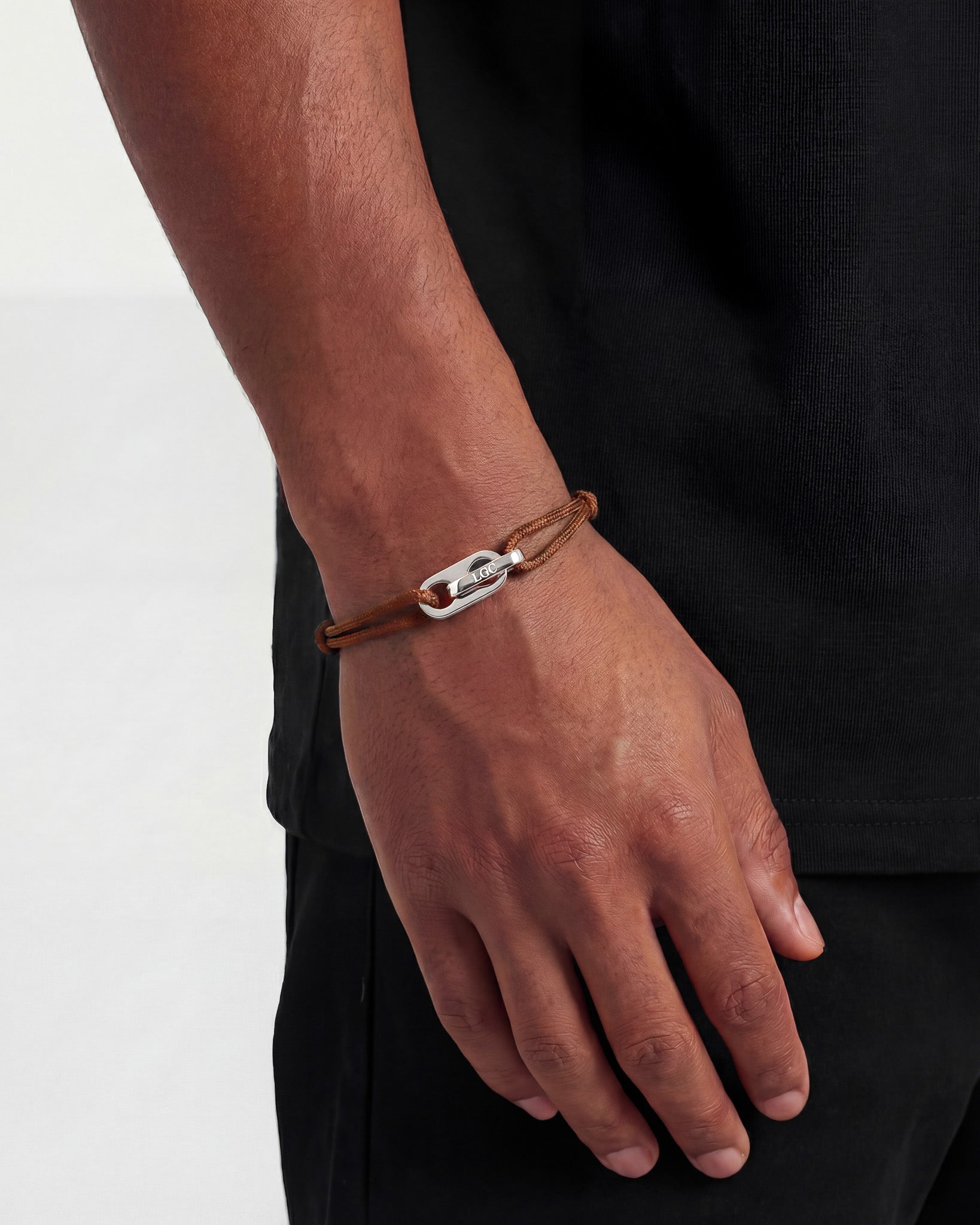 Atlantis silver bracelet shown on a wrist with a brown cord and silver clasp