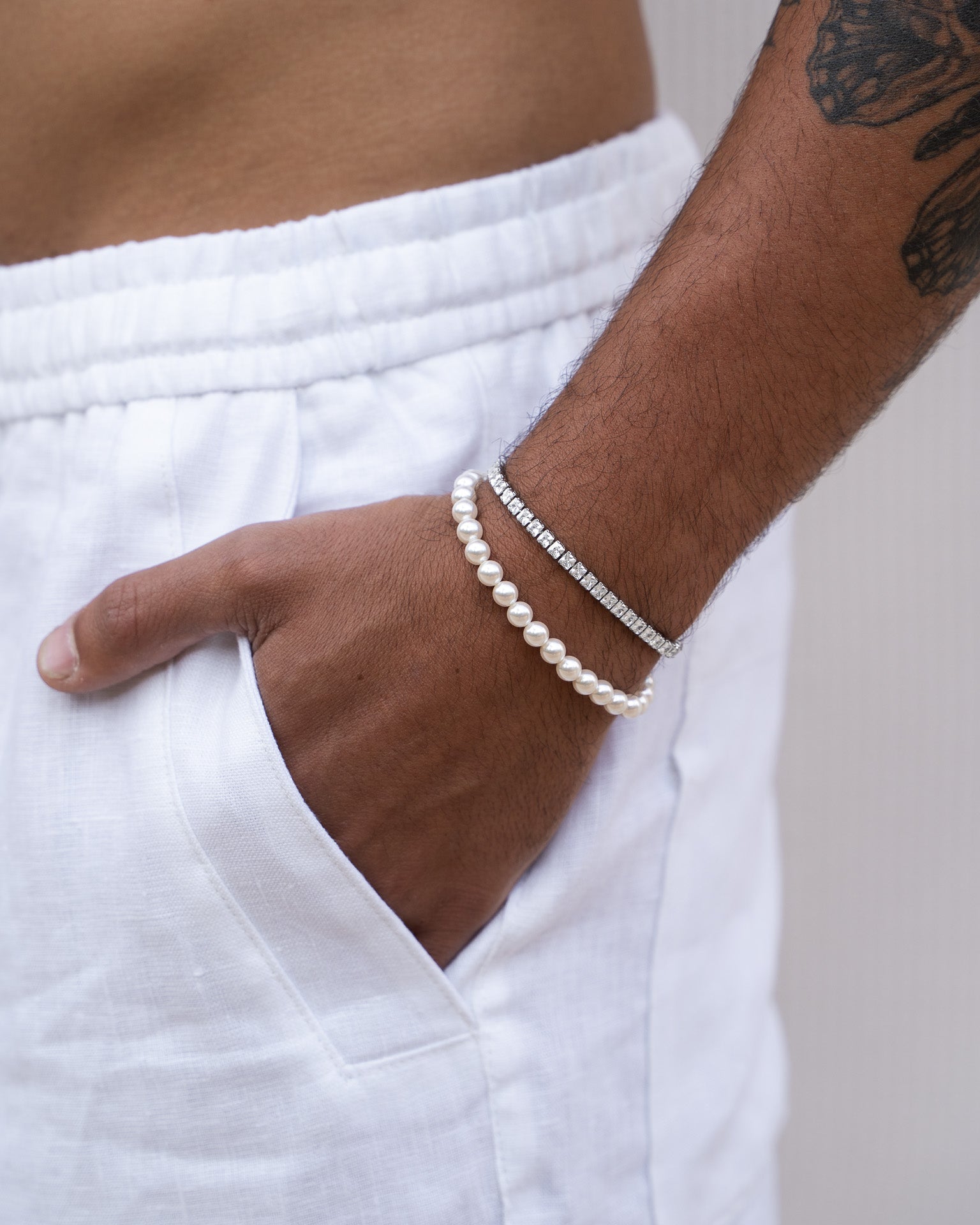Bellagio Pearl Silver Bracelet with 5mm pearls paired with a diamond bracelet on a white-sleeved wrist