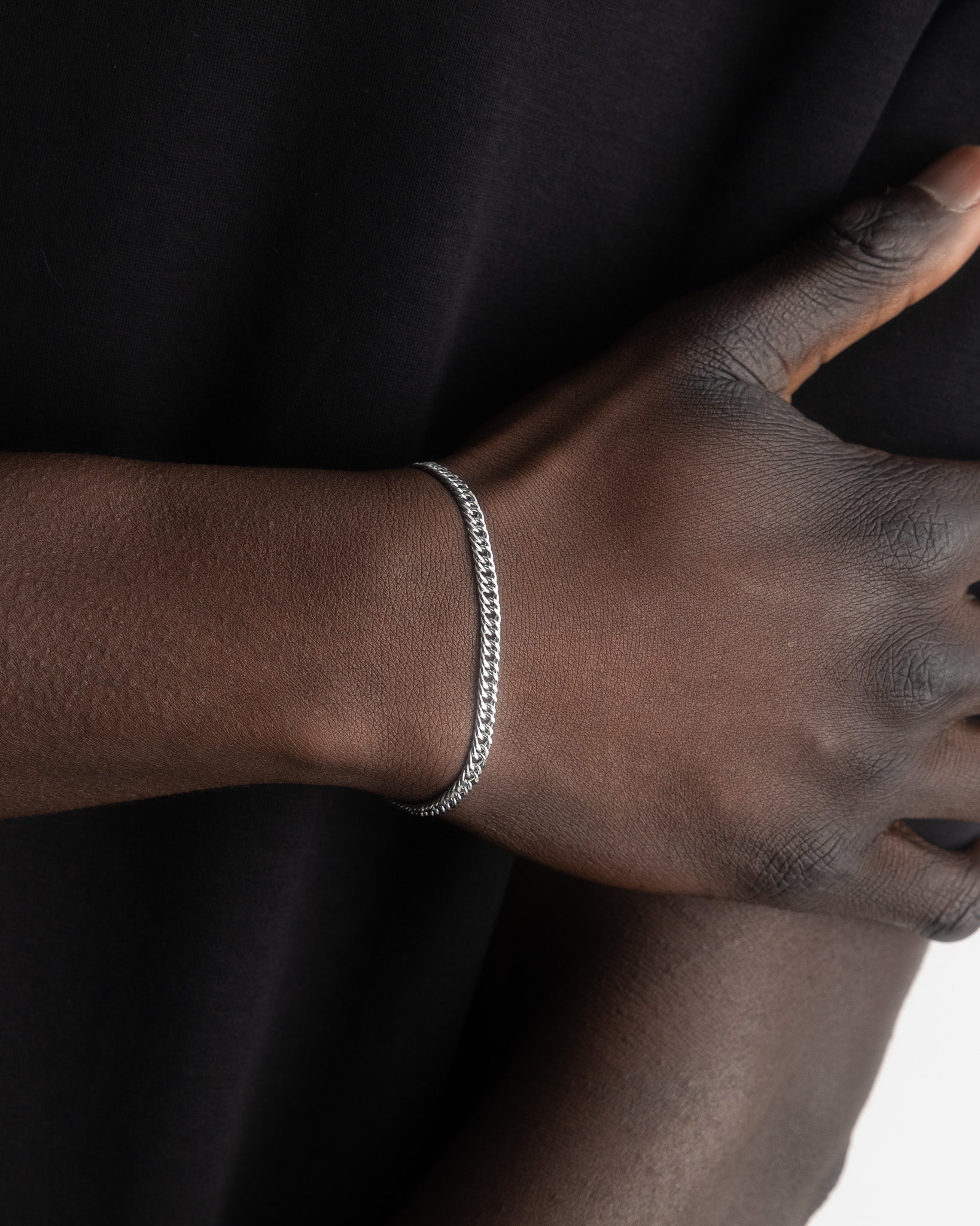 Silver chain bracelet worn on a model's wrist with black clothing