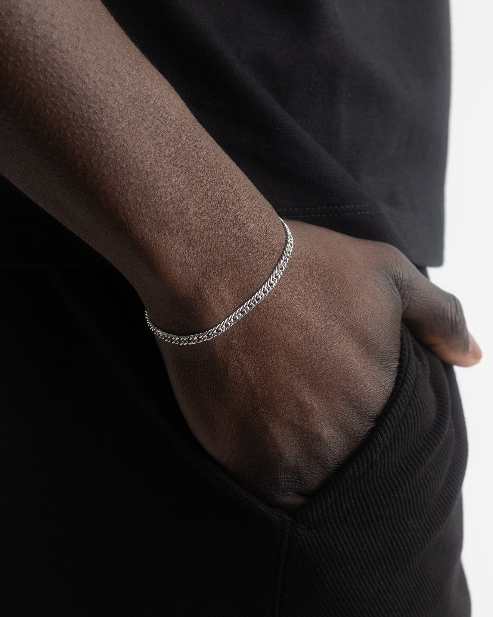 Coral silver bracelet wrapped around a model's wrist against black fabric.