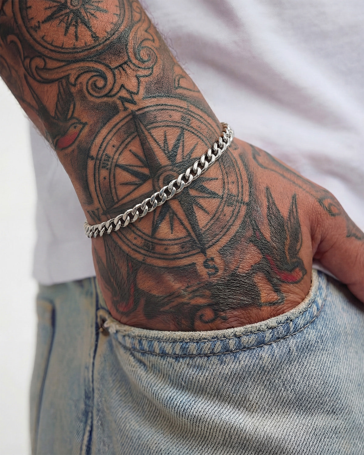 Cuban link silver bracelet worn on a tattooed wrist
