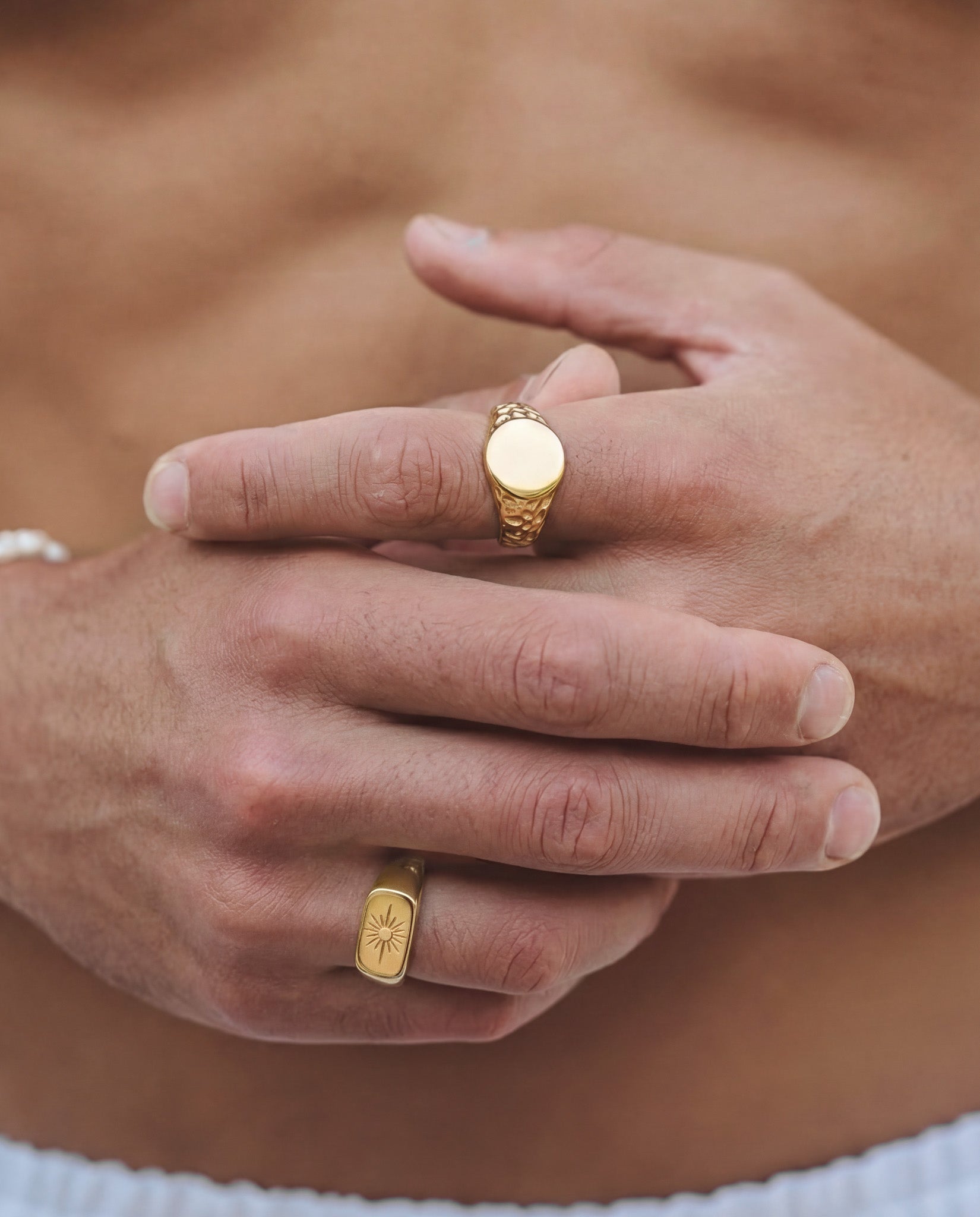 Gold horizon ring with a textured band and smooth circular top on a finger
