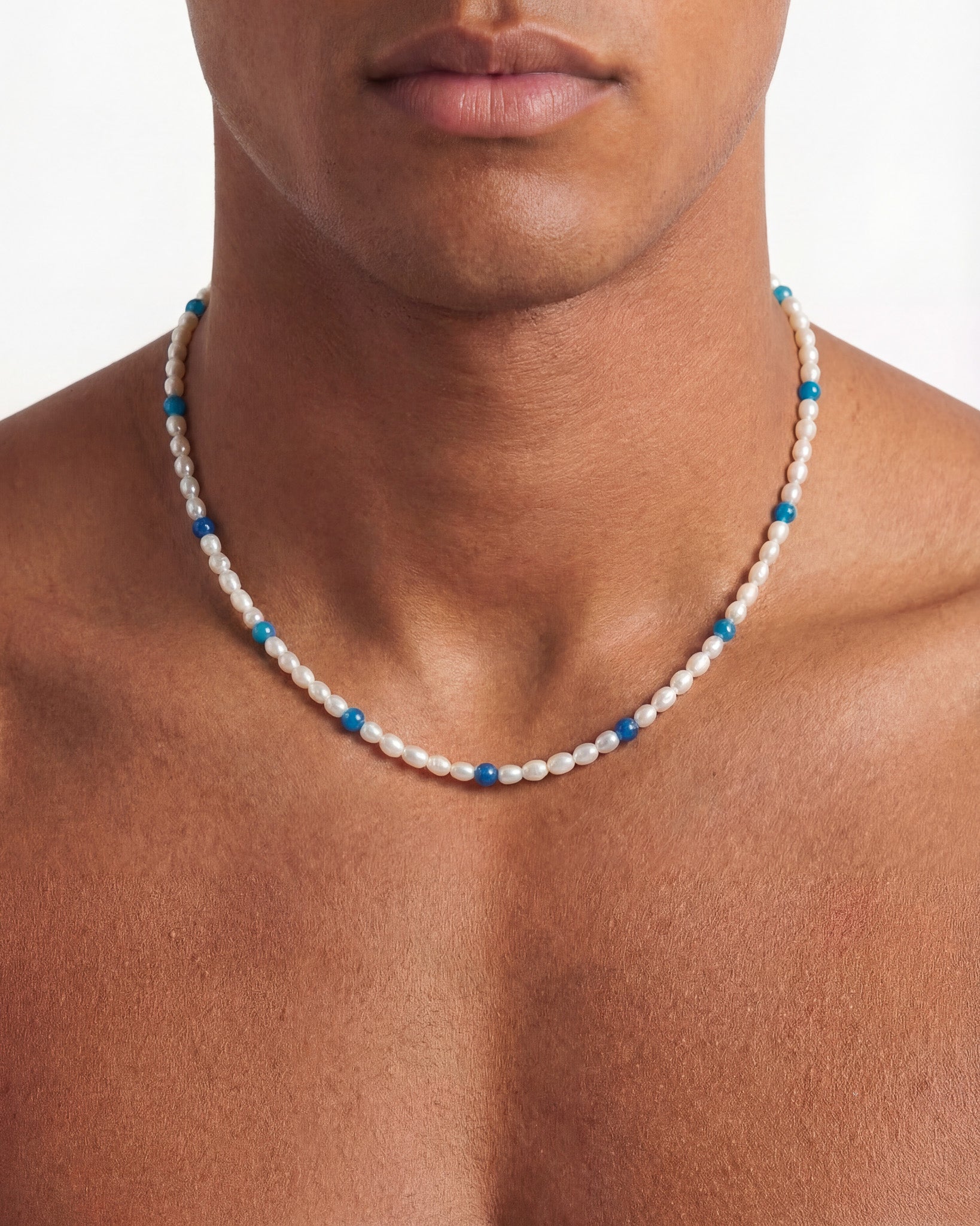 Close-up of a person wearing a GILI Pearl Silver Chain necklace with white pearls and blue beads.