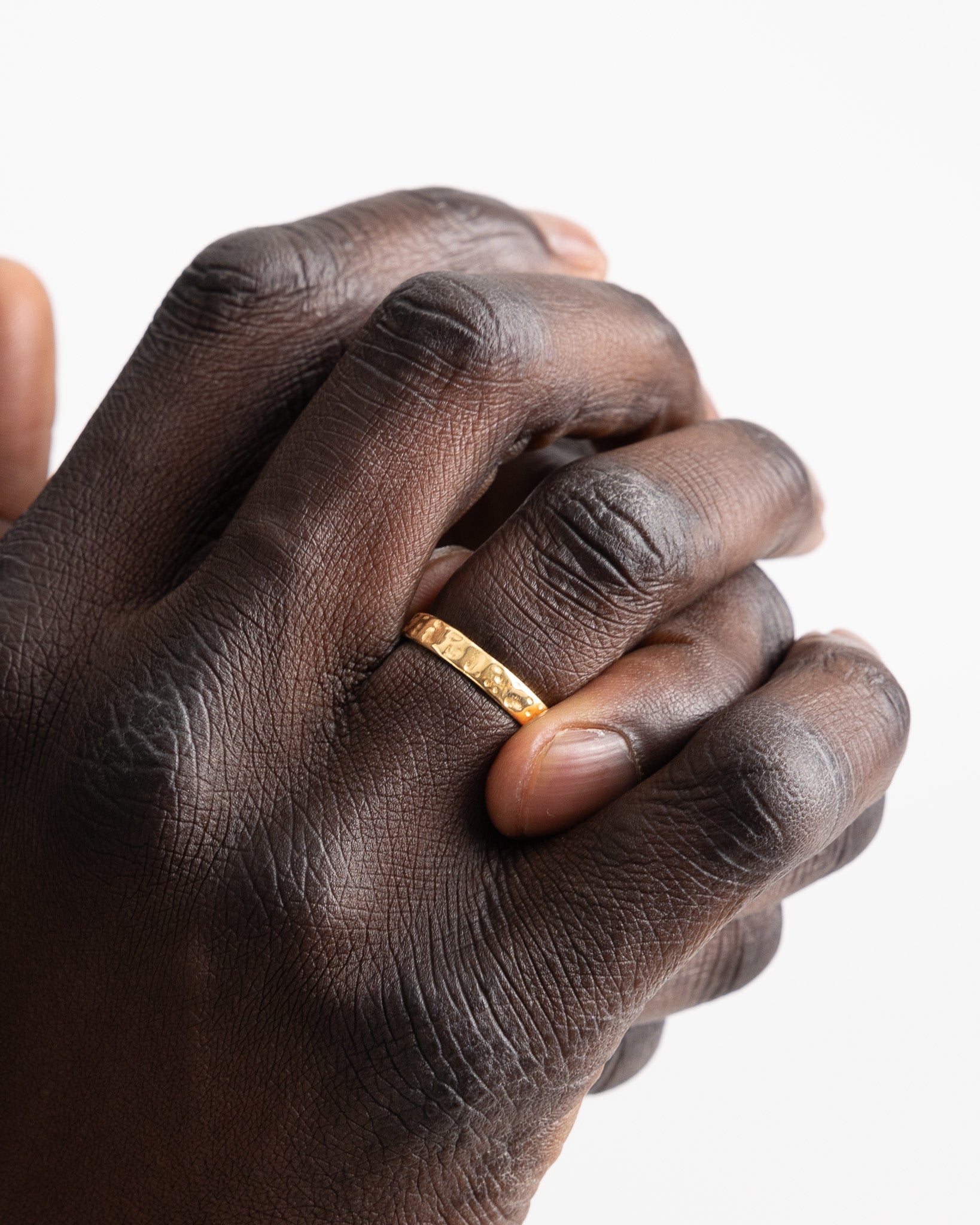 Hammered gold ring on finger of a dark skinned hand