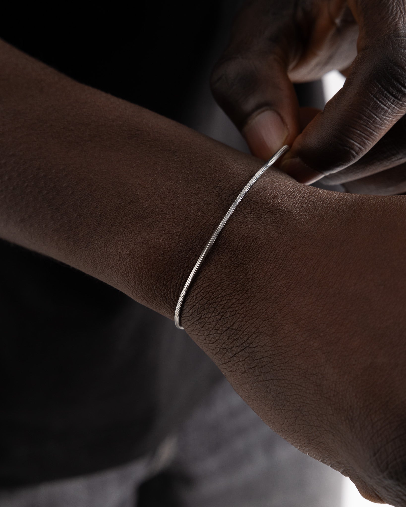 Lima silver bracelet shown in close up with a slim simple chain around the wrist