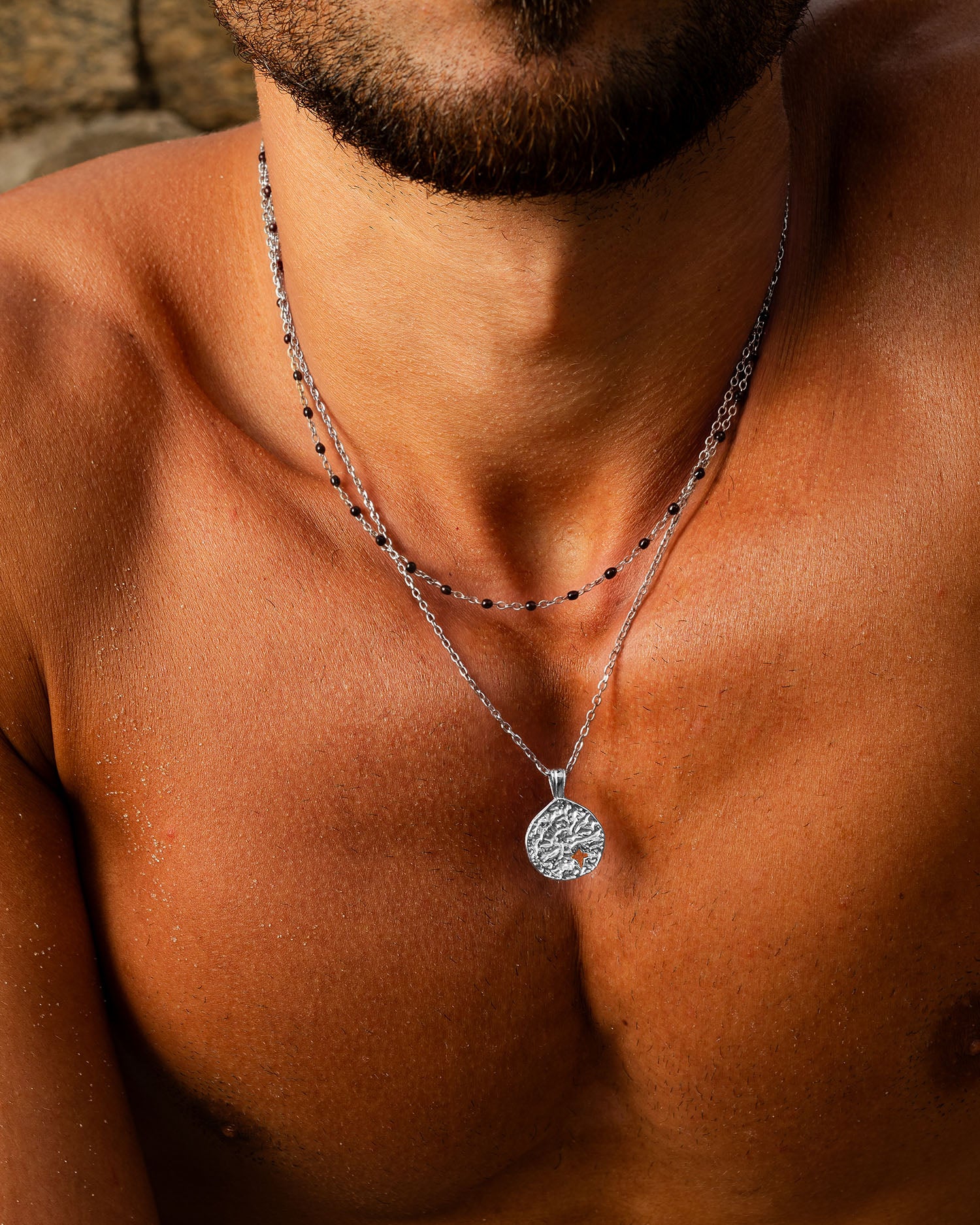 Mist silver necklace with two chains and a textured round pendant on a tanned neck