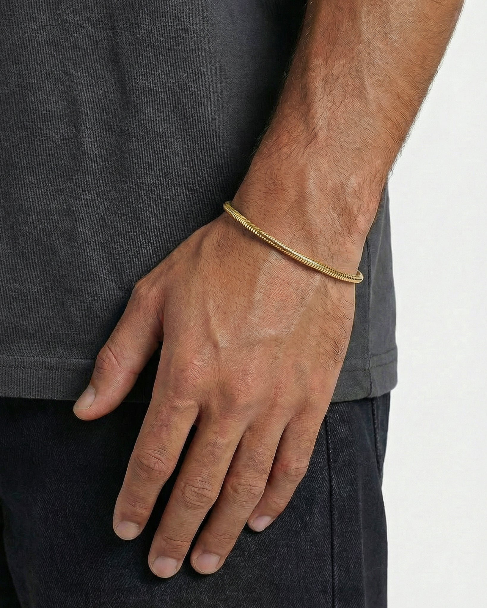 Sunset Gold Bracelet on a man's wrist against a dark shirt.