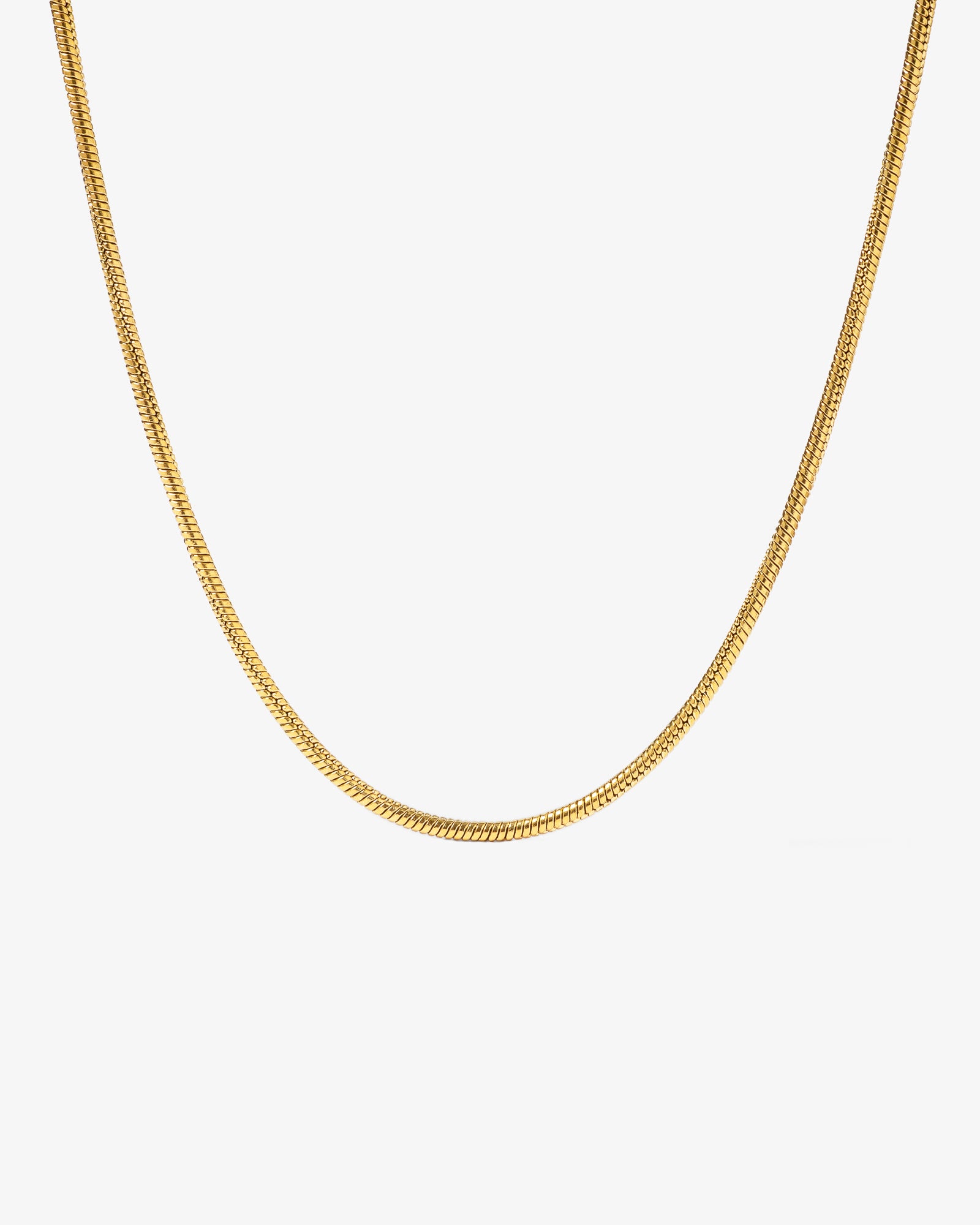 Sunset gold chain with 2 mm wide links laid across a light stone background