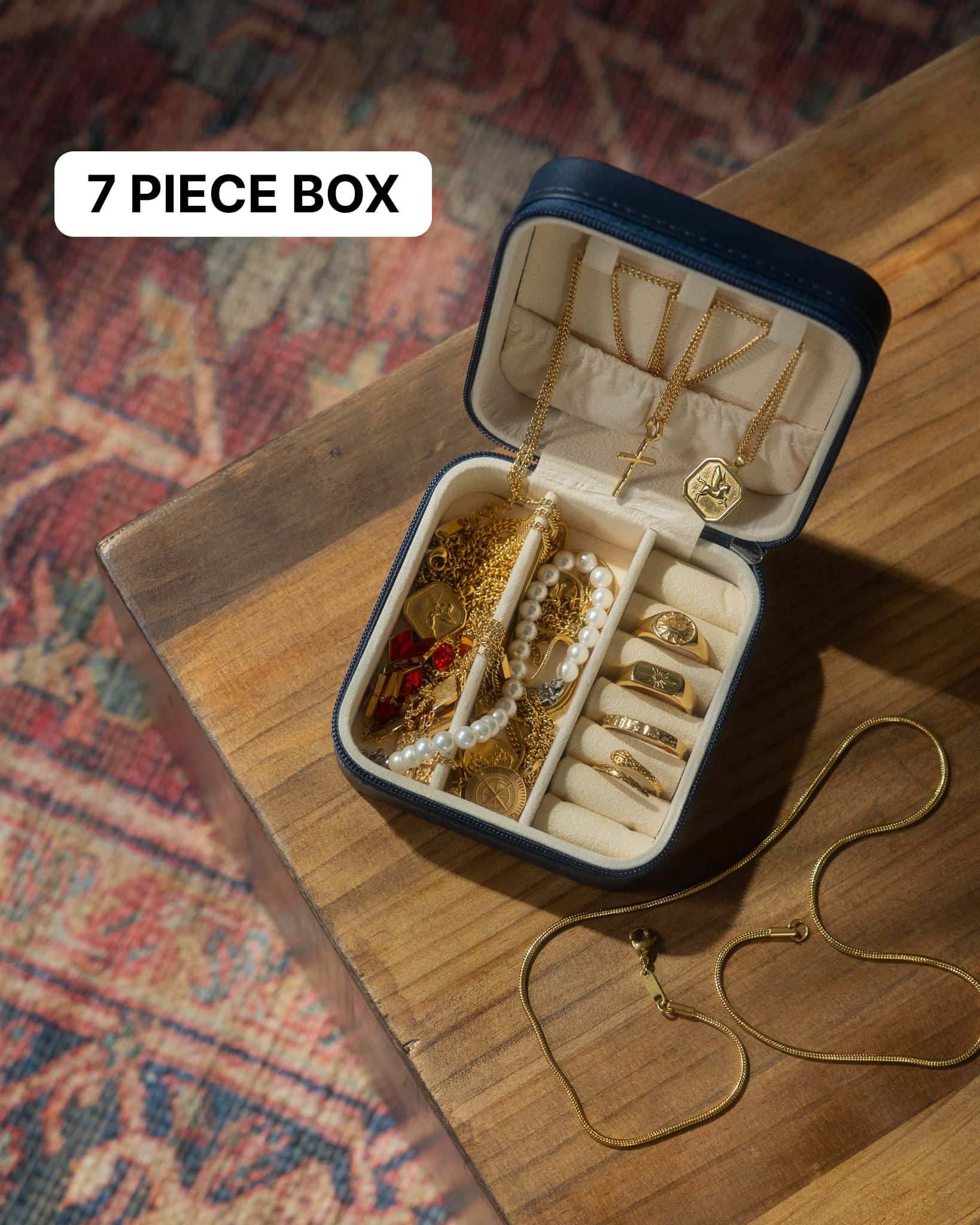 Open jewelry box reveals gold chains and charms on a wooden surface under a 7 piece box label.