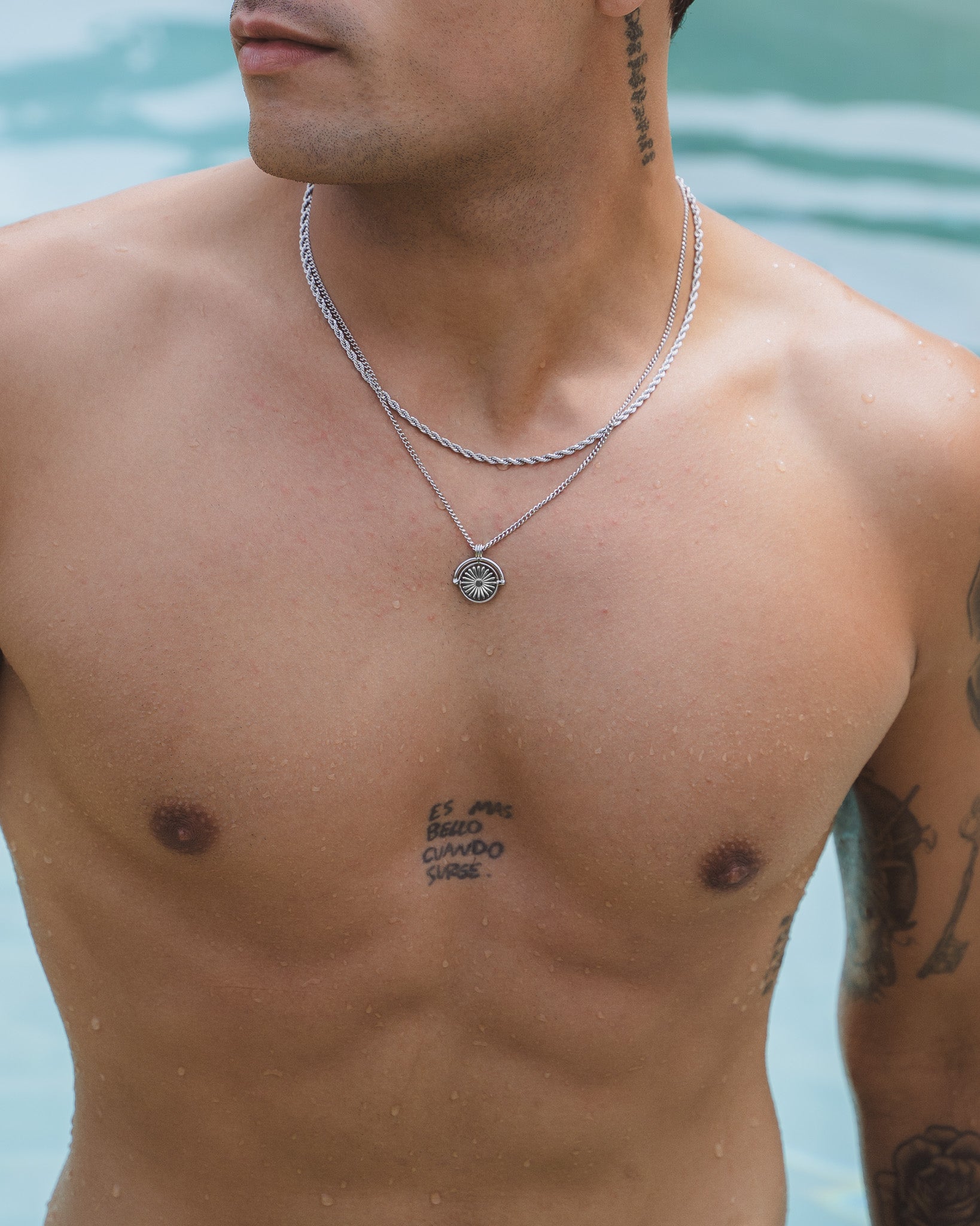 Two silver Daisy necklaces around a man's neck in a close up portrait.