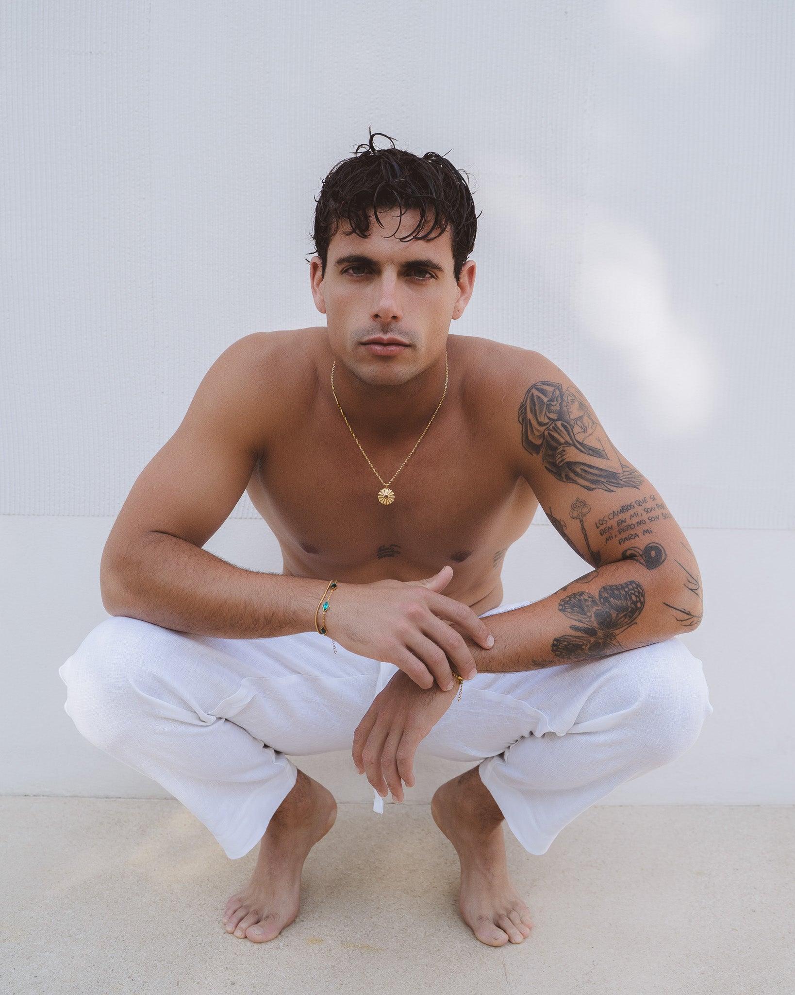 Male model wearing the silk gold necklace with a sunburst pendant