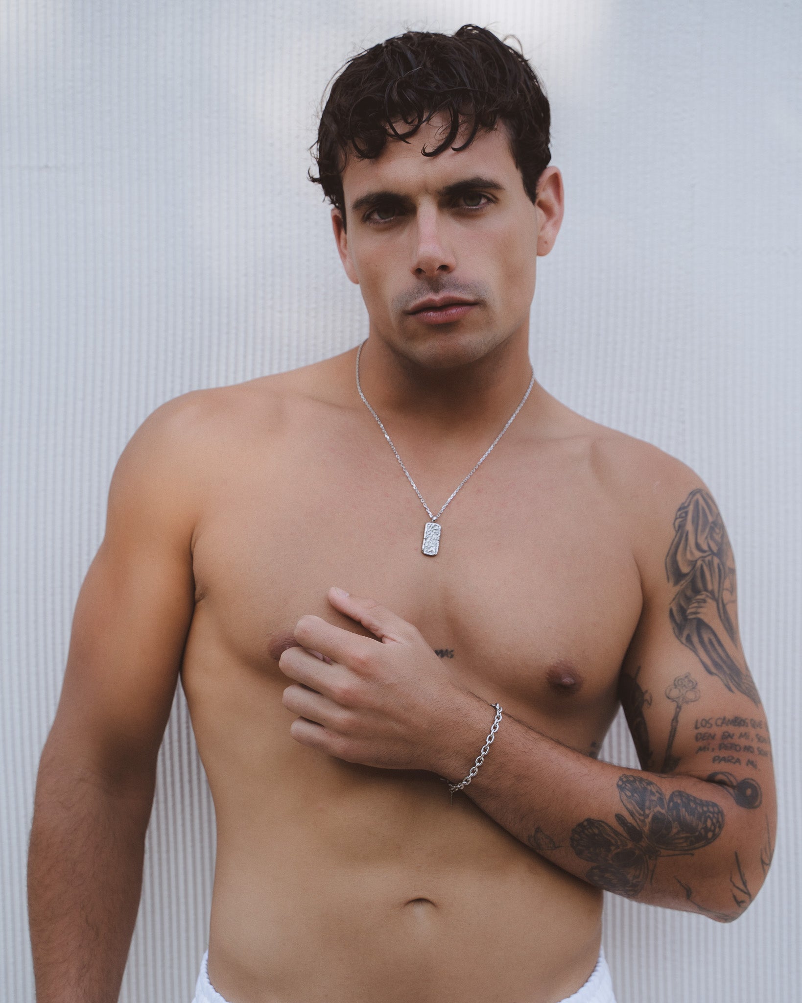 Man wearing a Moonrock Silver Necklace with a circular sunburst pendant on his bare chest