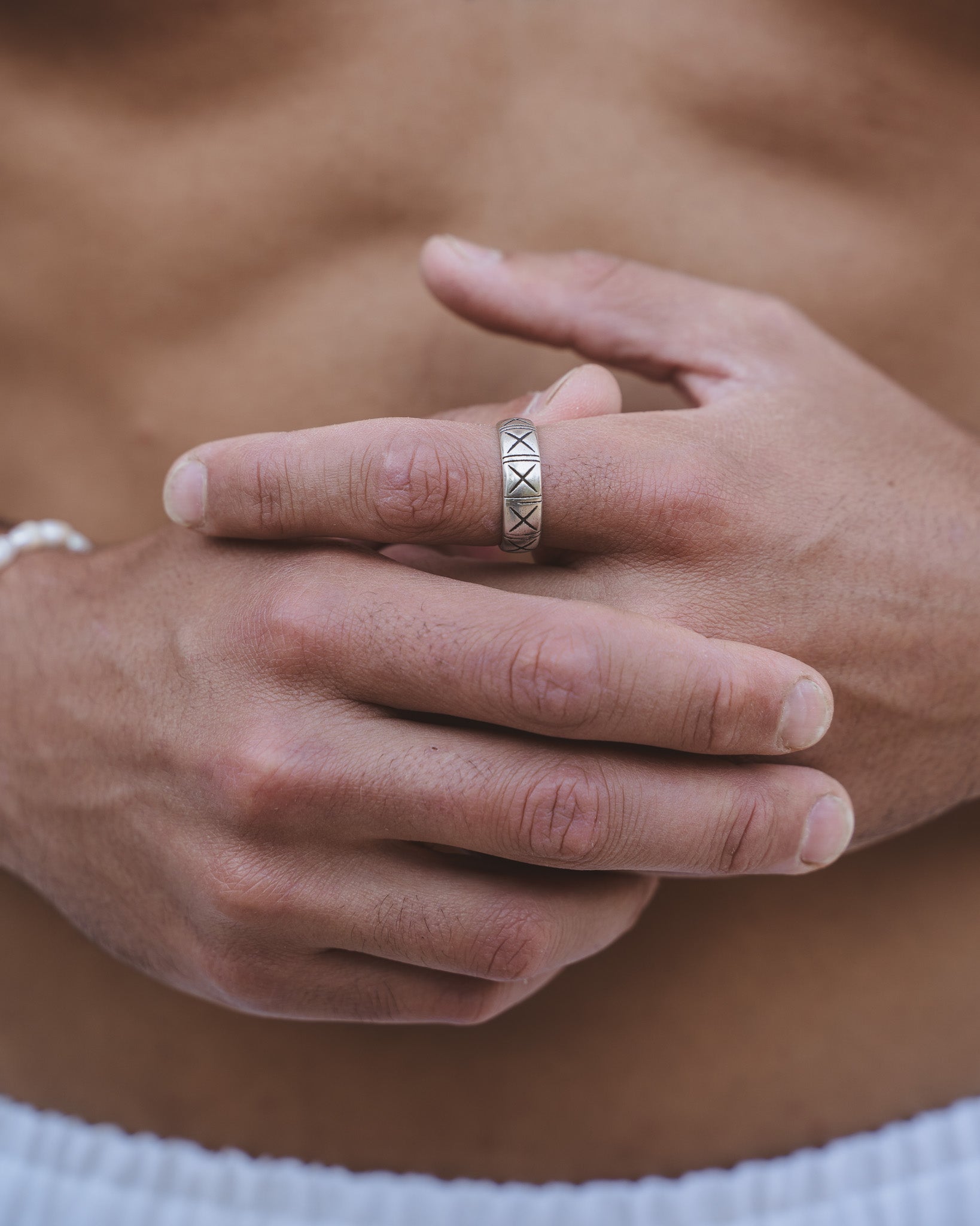 Hand wearing the TNF Silver Ring on the finger with a silver pendant necklace visible on the chest