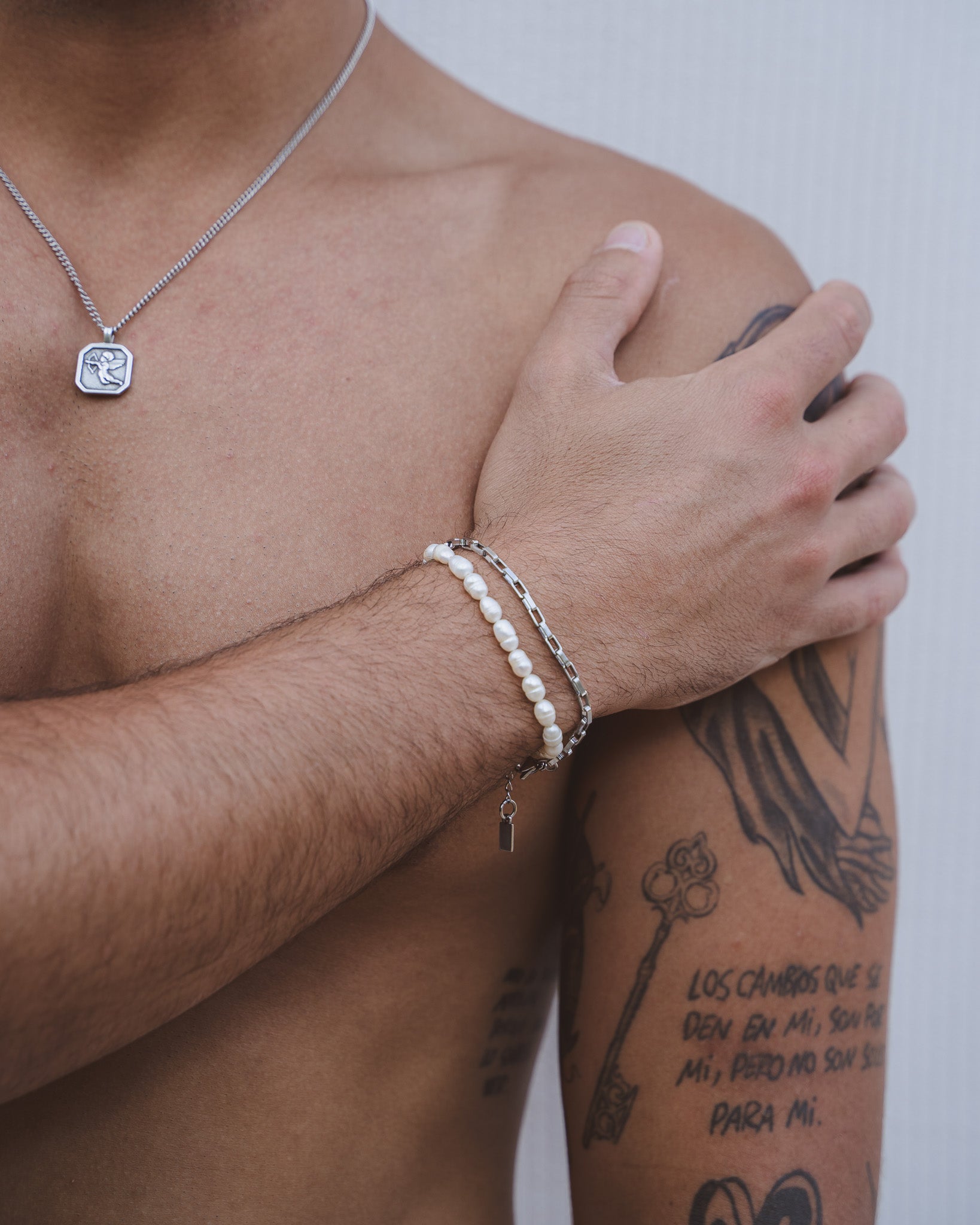 Silver Capri pendant necklace with a square engraved charm resting on a man's chest