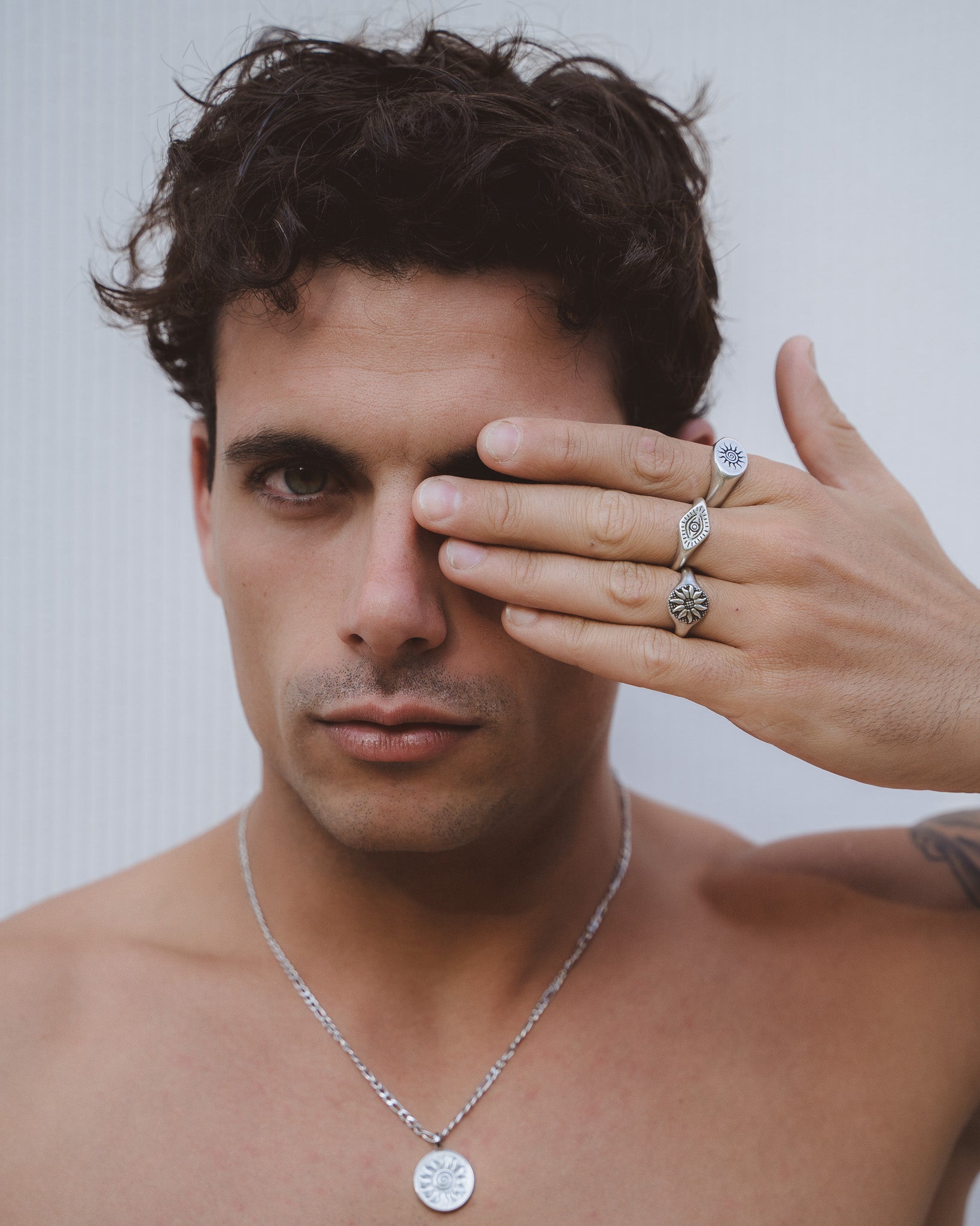 Close up of a man wearing Fleur Silver Ring stack with sun and eye motif rings