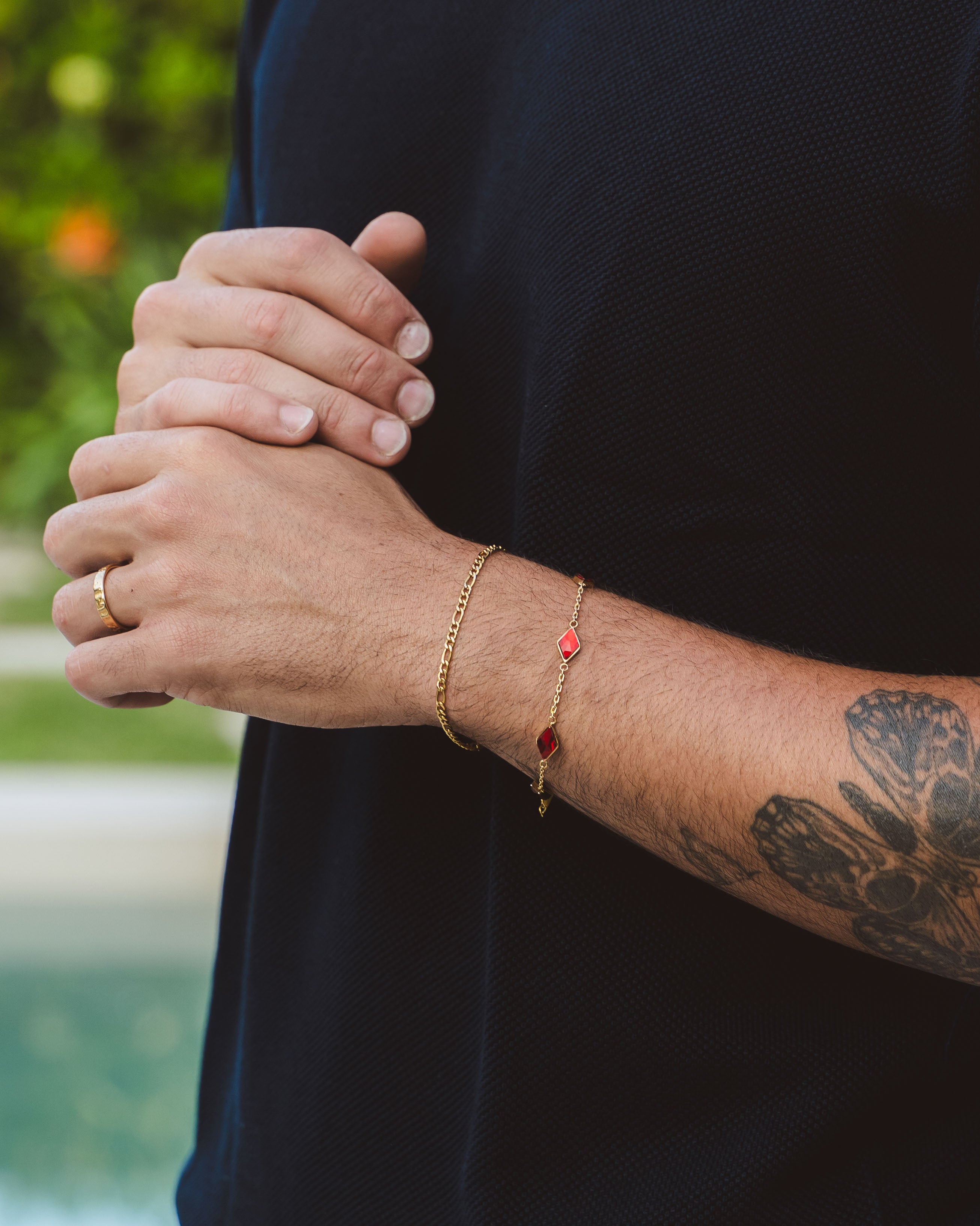 Amalfi Gold Bracelet with adjustable chain clasp and red gemstone charm on a dark shirt