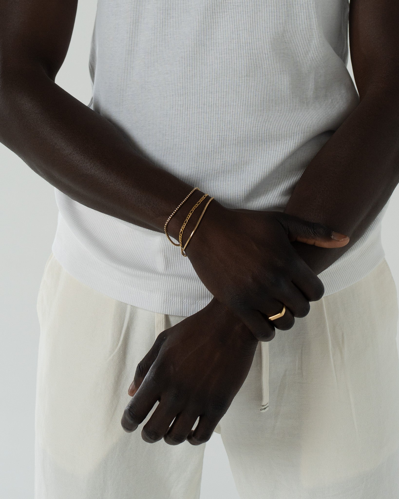 Lima gold bracelet worn with layered bracelets on a model in a white top