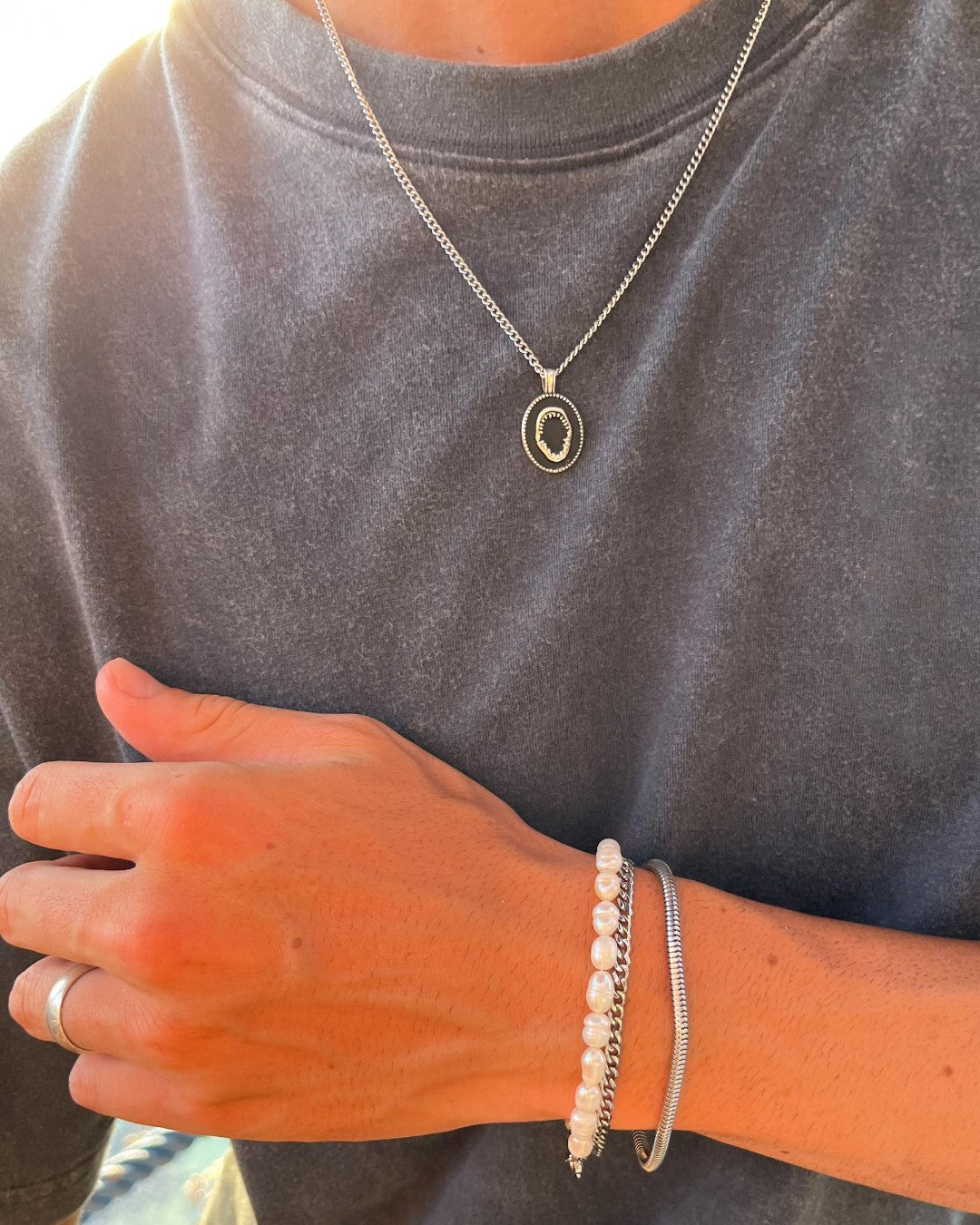 Lombok silver shark jaw pendant necklace shown over a gray top with layered chains