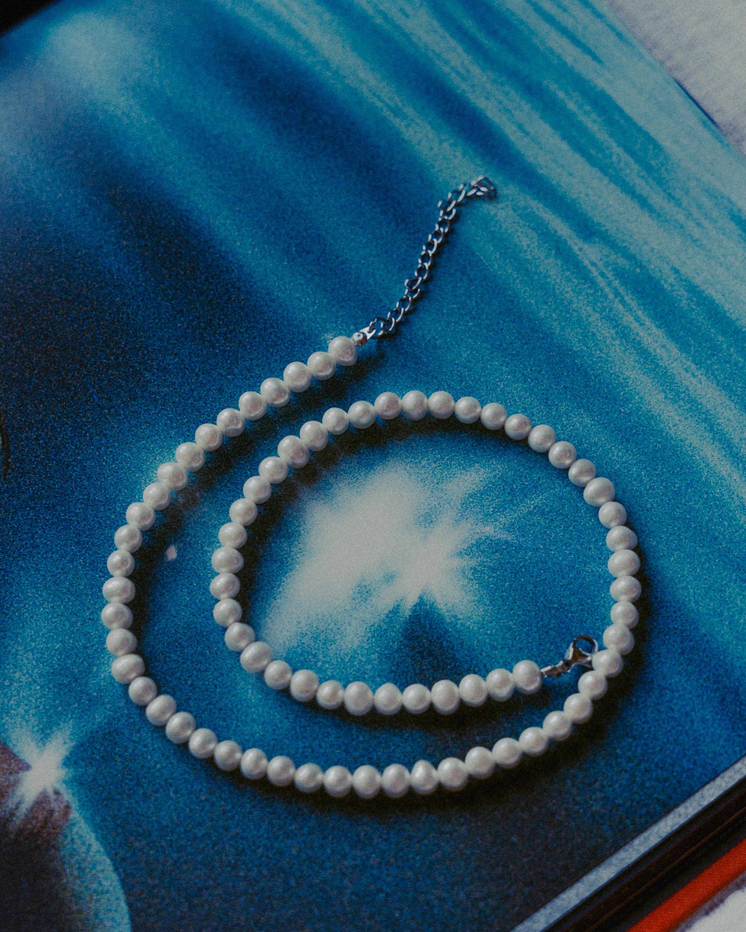 Close-up of Bellagio Pearl Chain with 5mm pearls on a blue surface.