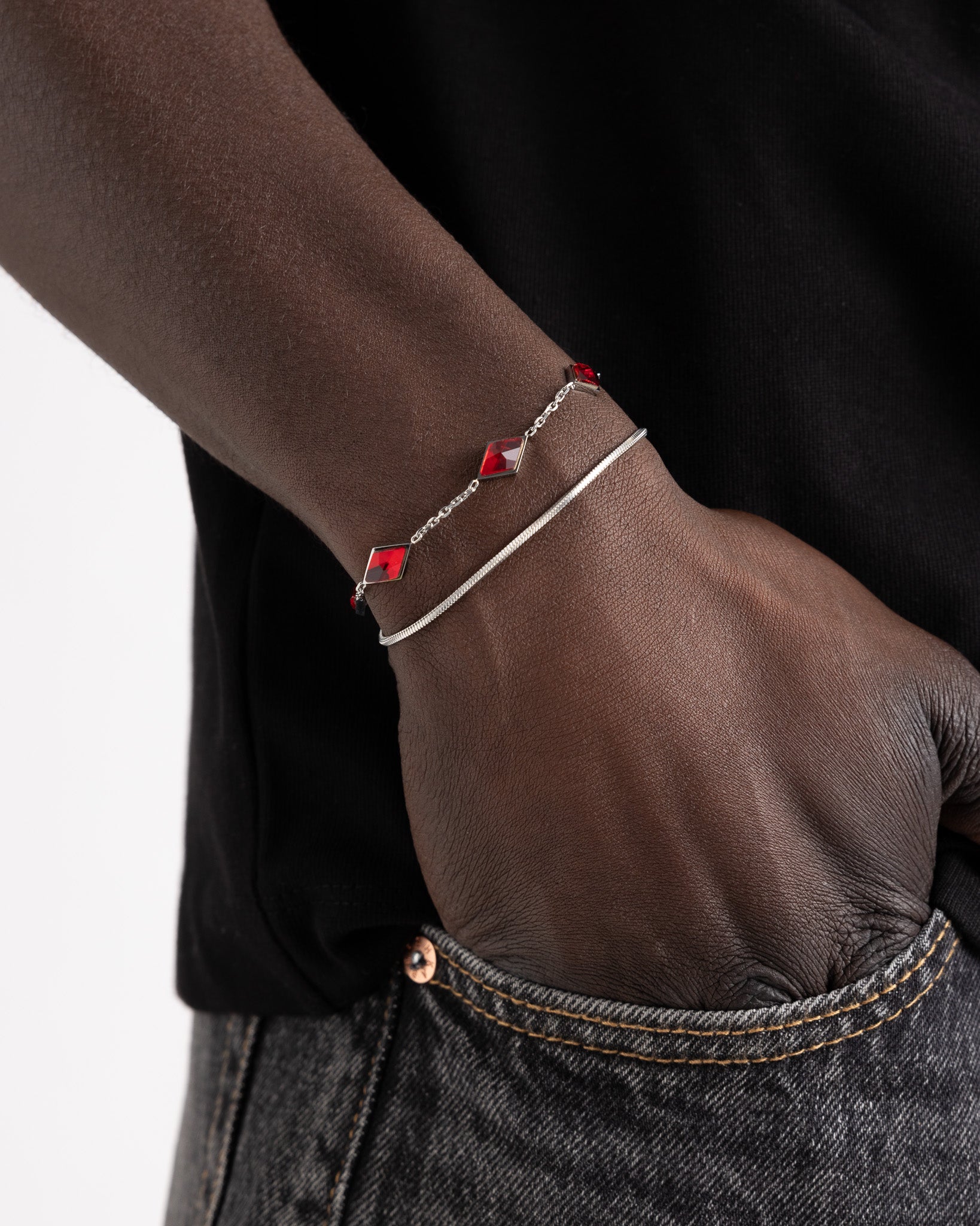Lima silver bracelet on dark skin with red gemstone accents along a delicate chain