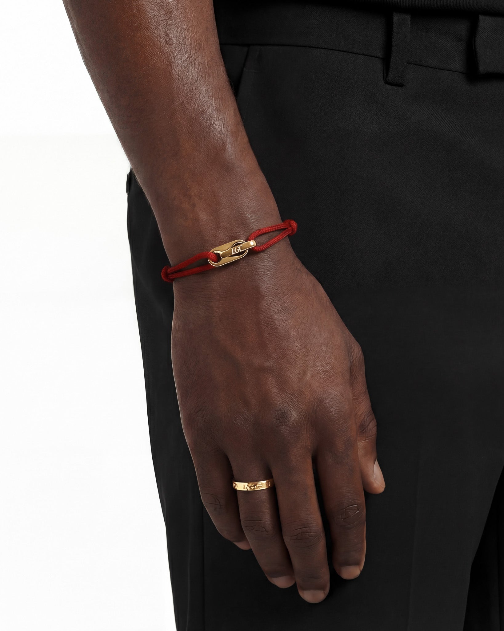 Atlantis gold bracelet with red cord on dark wrist and engraved LGC clasp