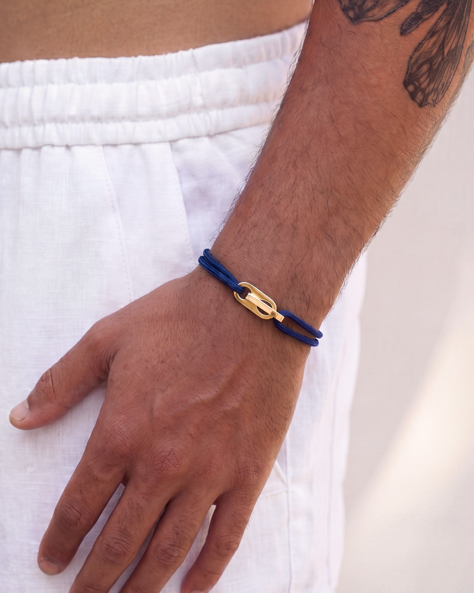 Atlantis gold bracelet with blue cord and a gold clasp on the wrist.