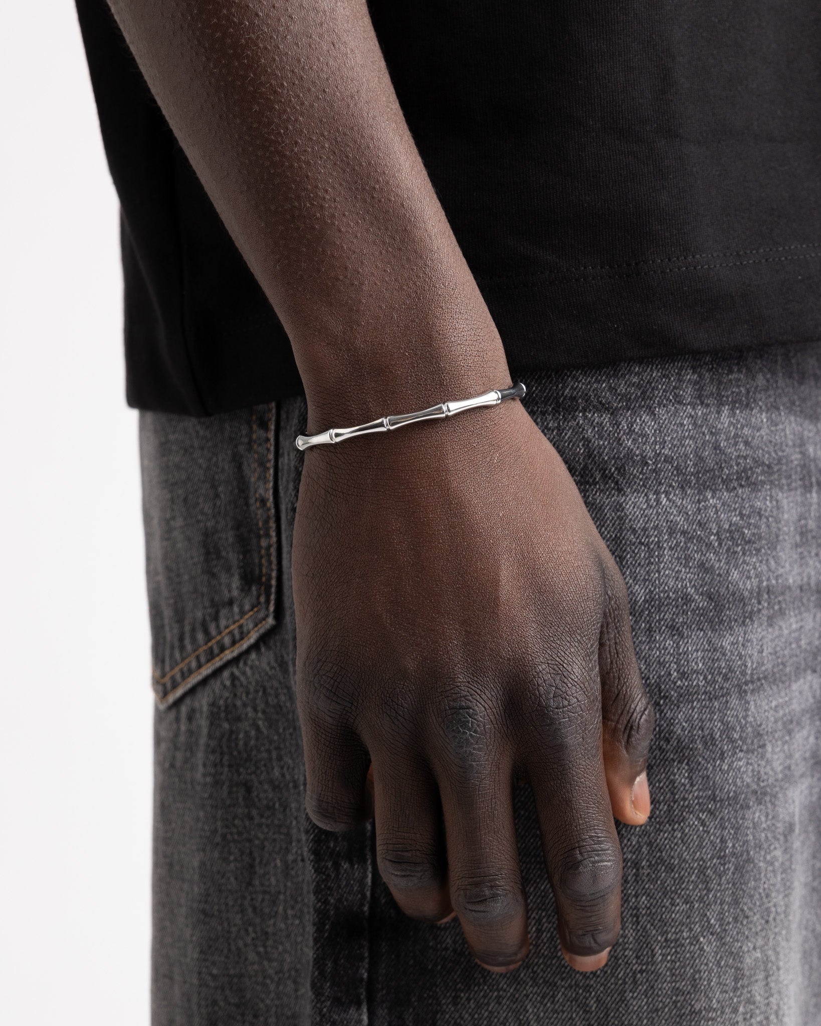 Bamboo styled silver bracelet on a model's wrist close up with a black sleeve