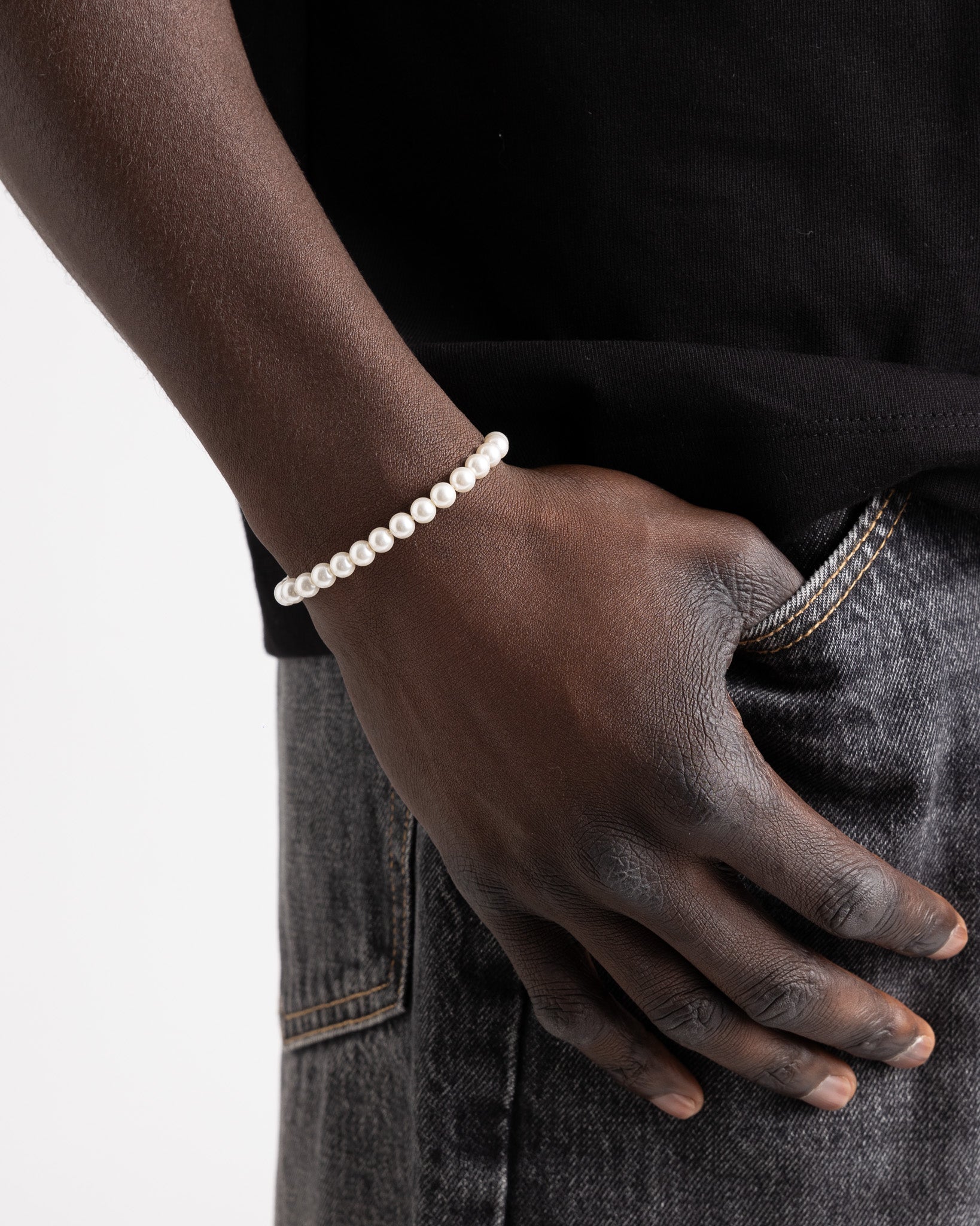 Bellagio pearl bracelet worn on a model's wrist showing the adjustable chain against dark clothing.