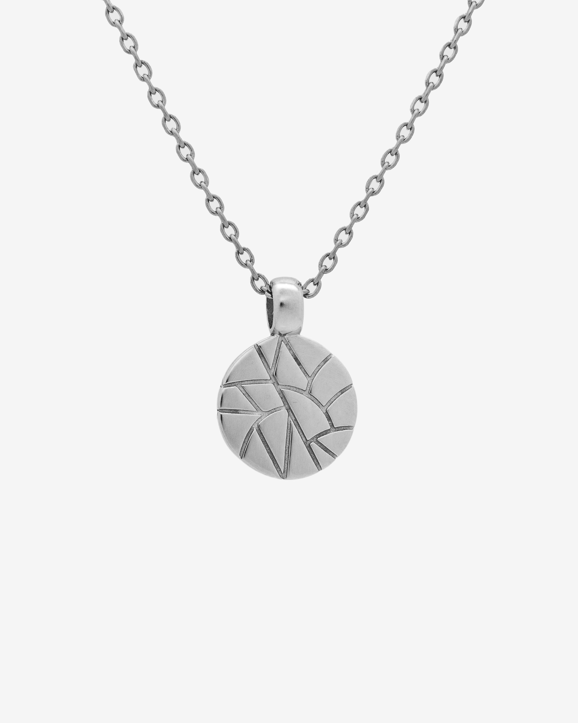 Broken silver necklace featuring a round textured pendant with geometric etched pattern.