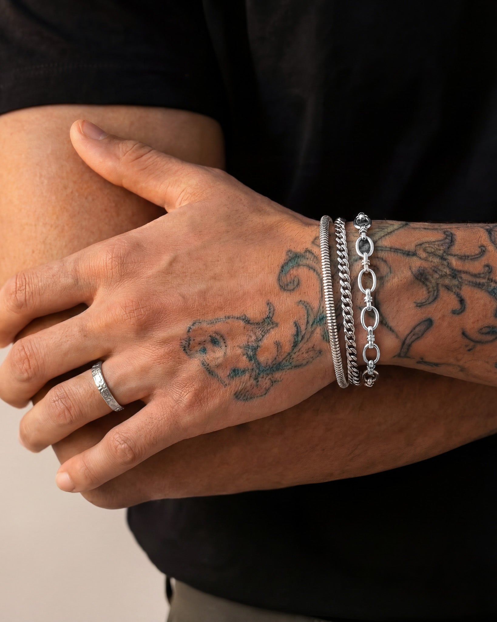 Tattooed forearm wearing multiple silver bracelets including the Sunset Silver Bracelet.