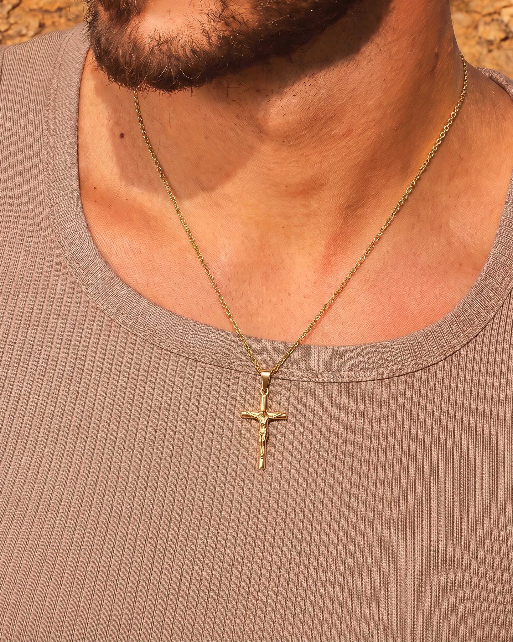 Gold crucifix necklace worn around the neck with chain visible