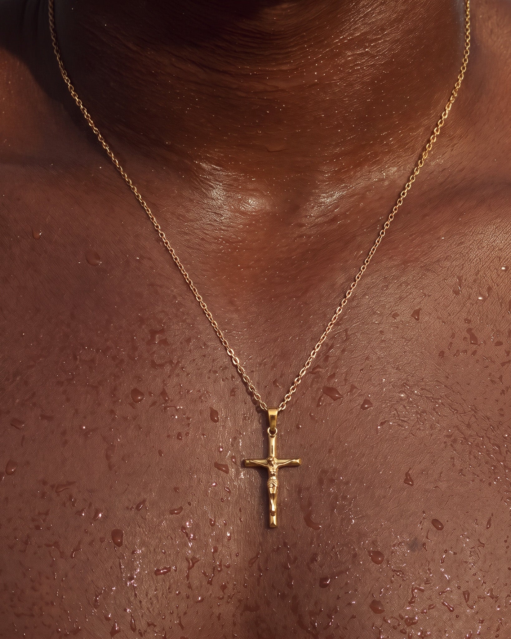 Gold crucifix necklace resting on chest with pendant visible