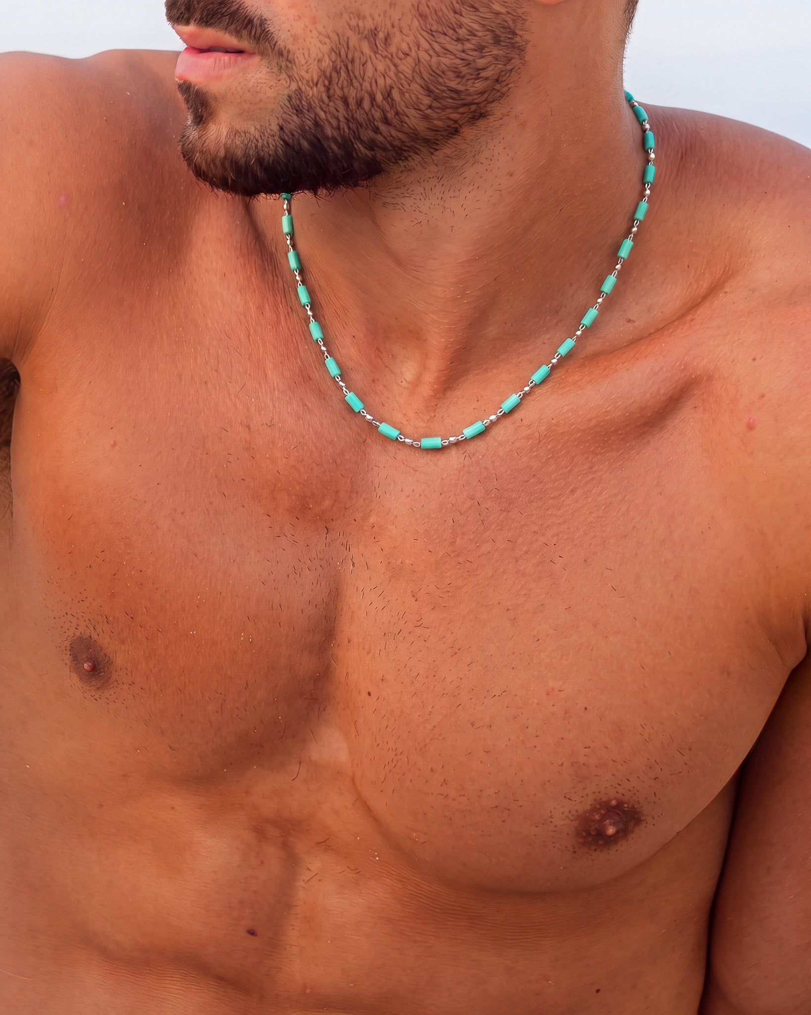 Man wearing turquoise cube bead necklace with silver chain around his neck