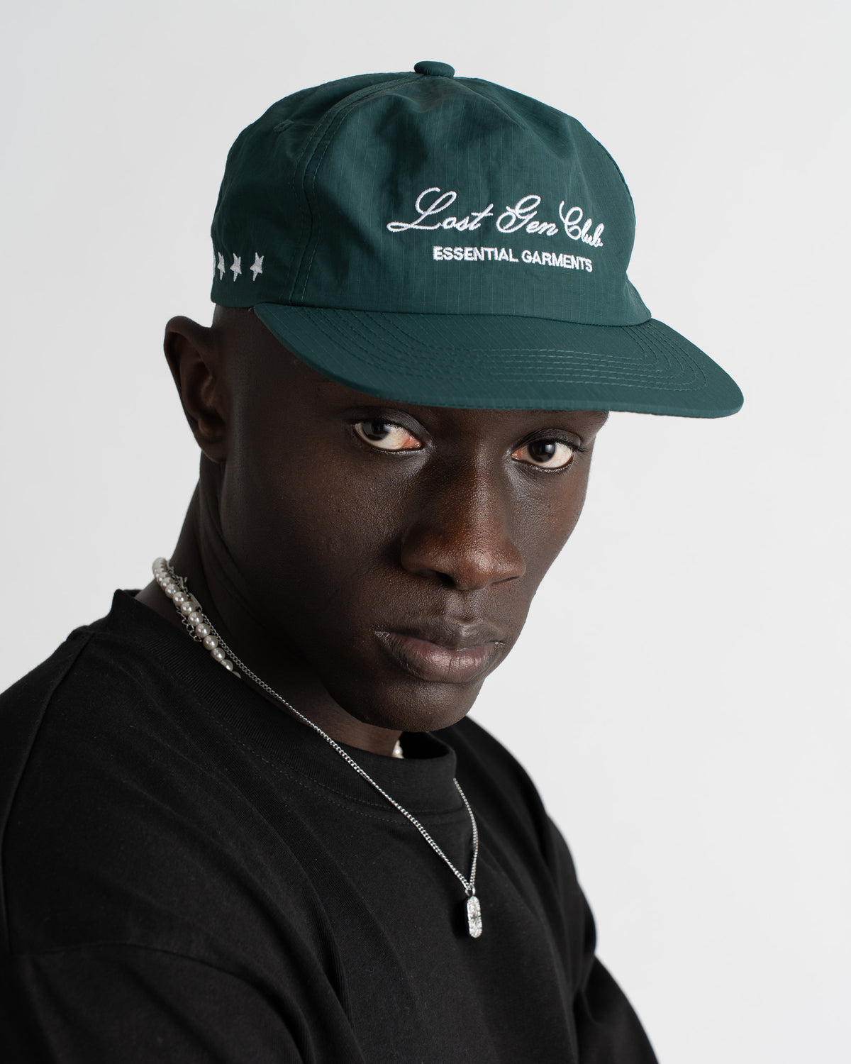 Close up of green nylon cap showing Lost Gen Club Essential Garments embroidery