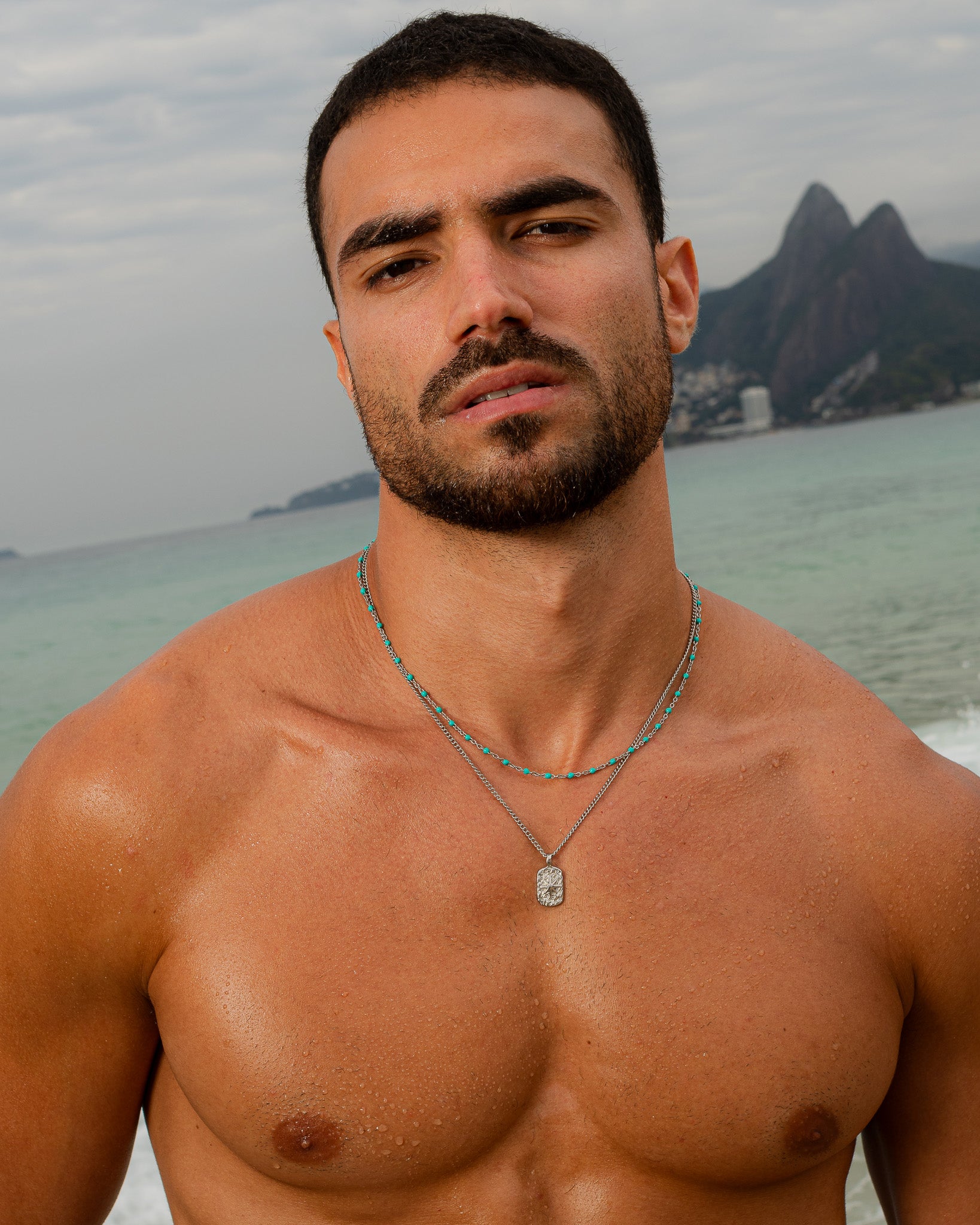 GEM Silver Chain necklace with turquoise beads worn by a man at the beach, multiple strands visible around the neck