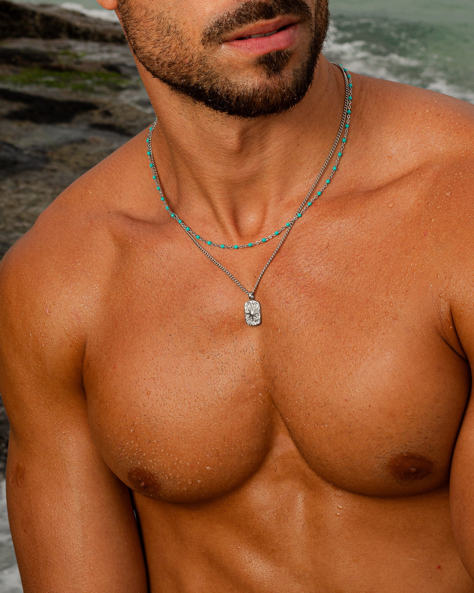 bearded man wearing a turquoise bead silver chain with a pendant on the chest