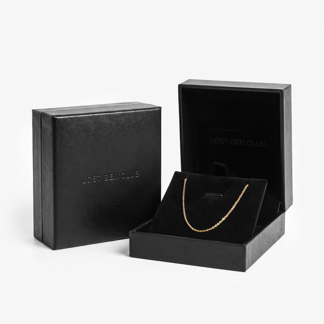 Black premium gift box shown closed and open, with LOST GEN CLUB embossed on the lid and a gold chain on the velvet insert