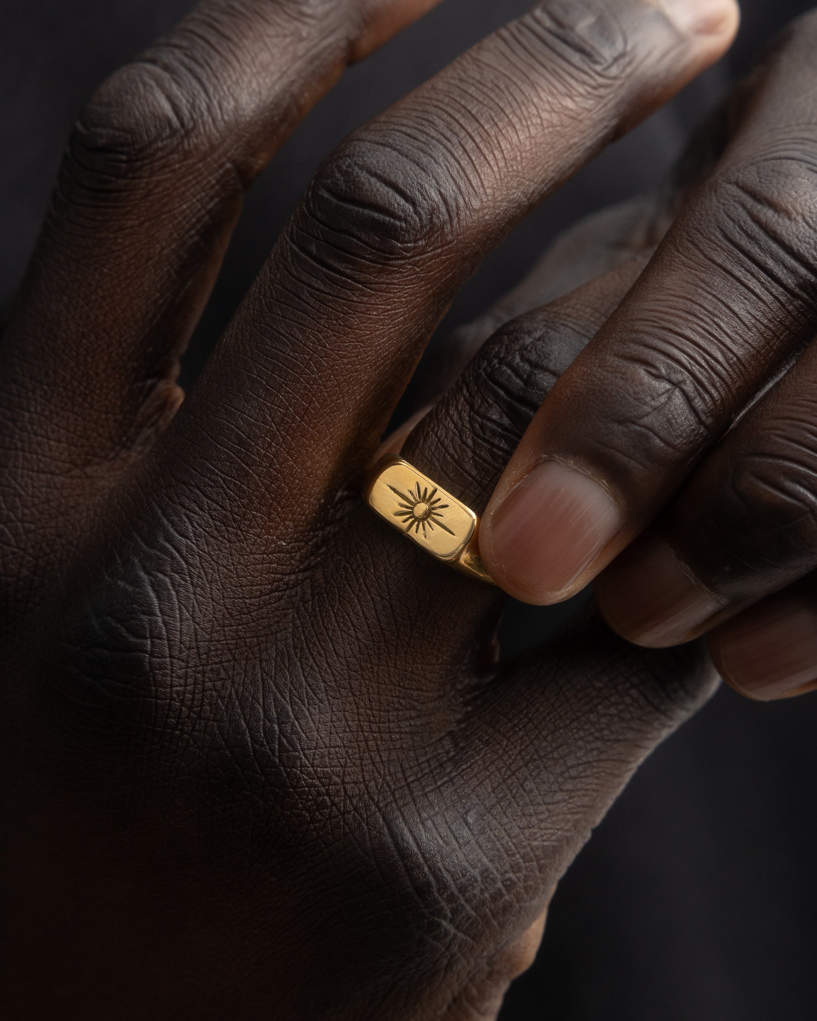 Close up of Horizon Gold Ring worn on finger with sunburst engraving