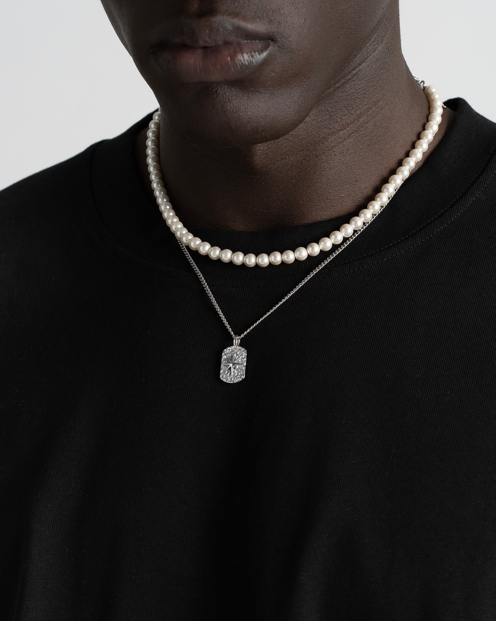 Ivory pearl necklace paired with a patterned silver chain around the neck