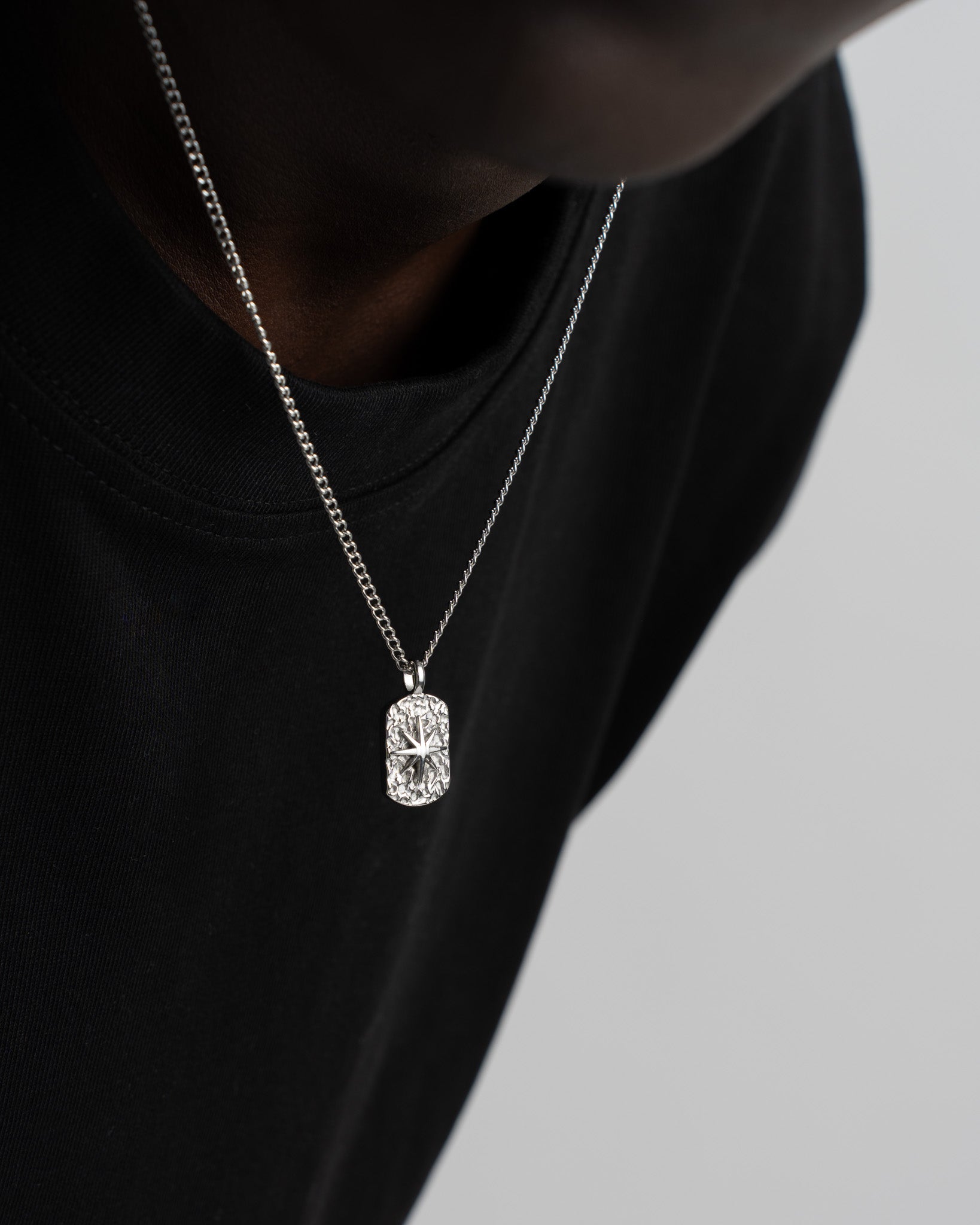 Front view of the IBZ Silver Necklace showing the rectangular crystal pendant resting on a black tee