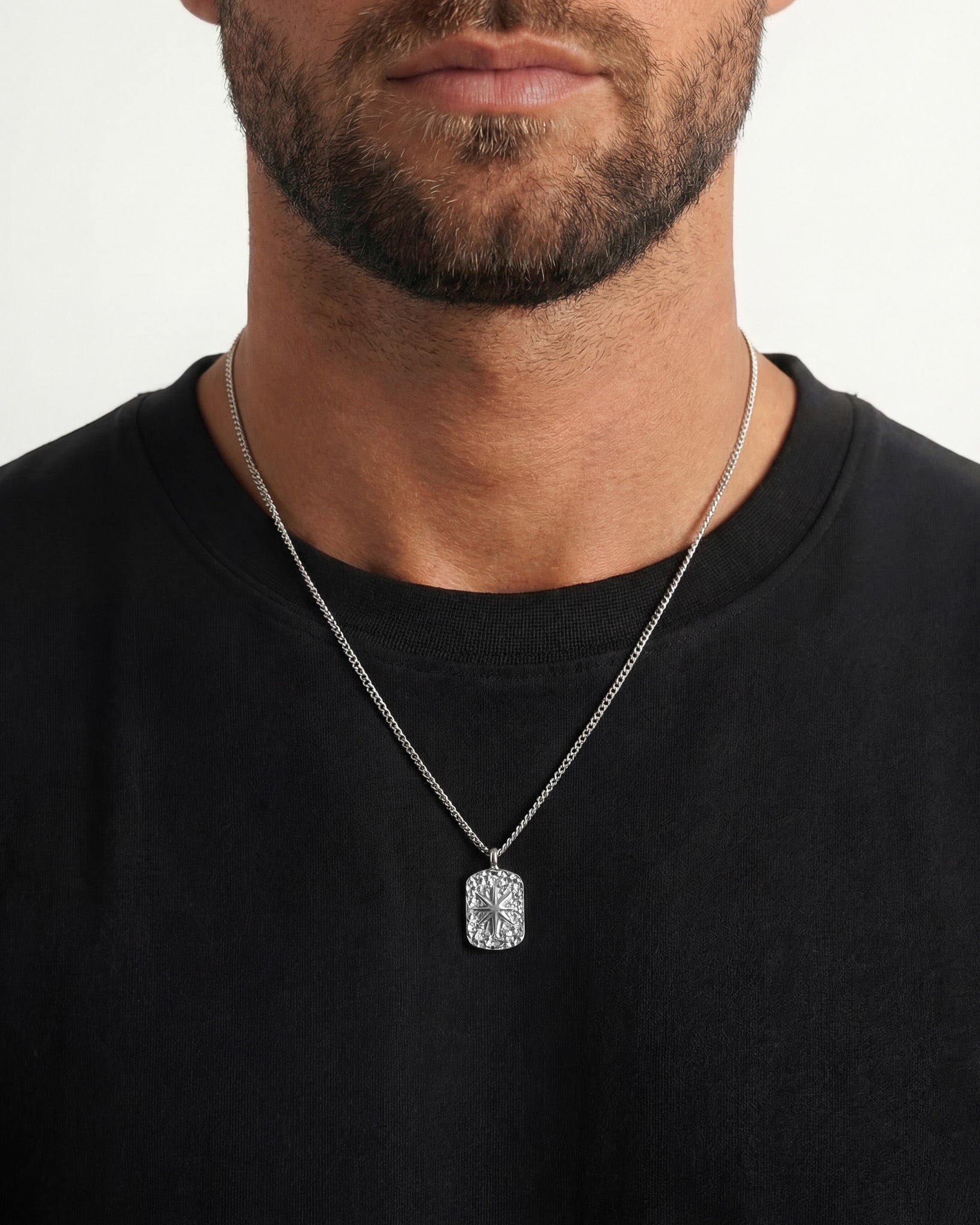 Close up of a man wearing an IBZ Silver Necklace with a crystal rectangular pendant against a black shirt