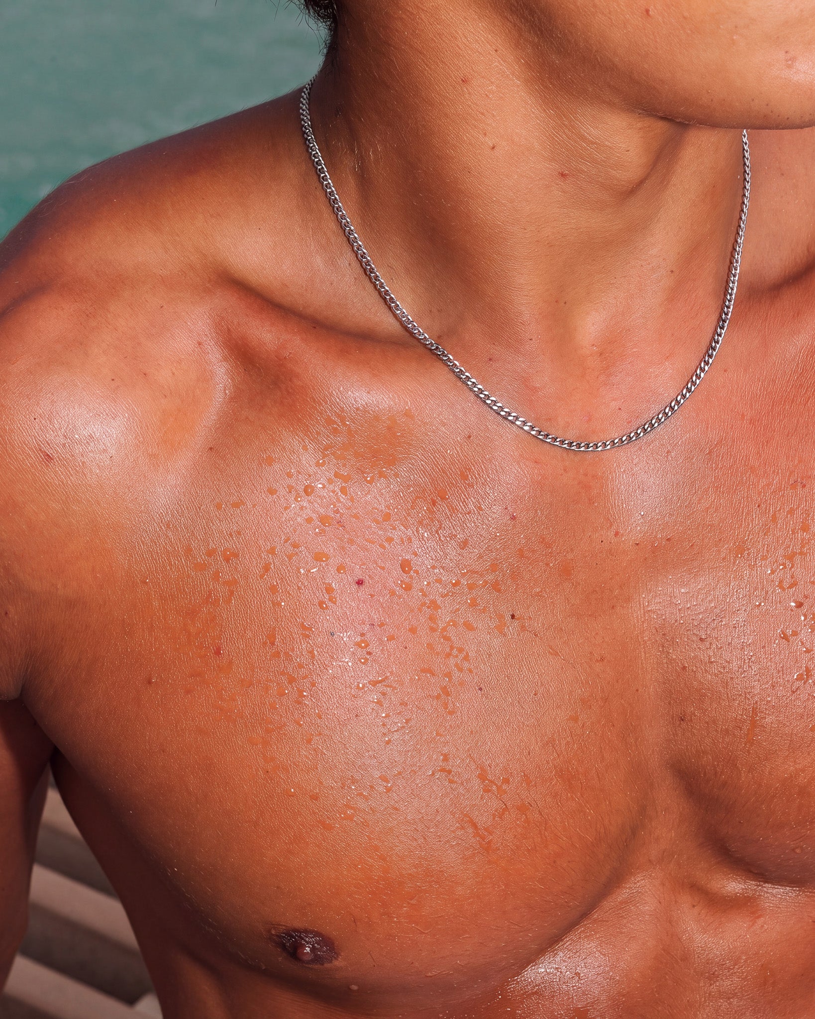 KUBU silver chain draped around a model's bare neck and collarbone.