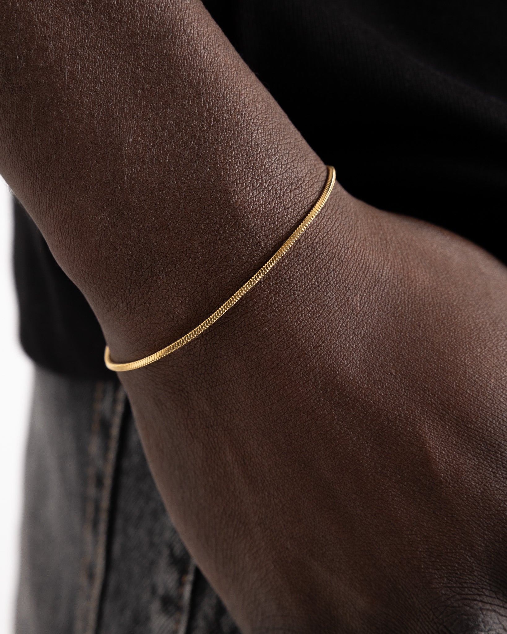 Close-up of a delicate Lima gold bracelet around a dark-skinned wrist
