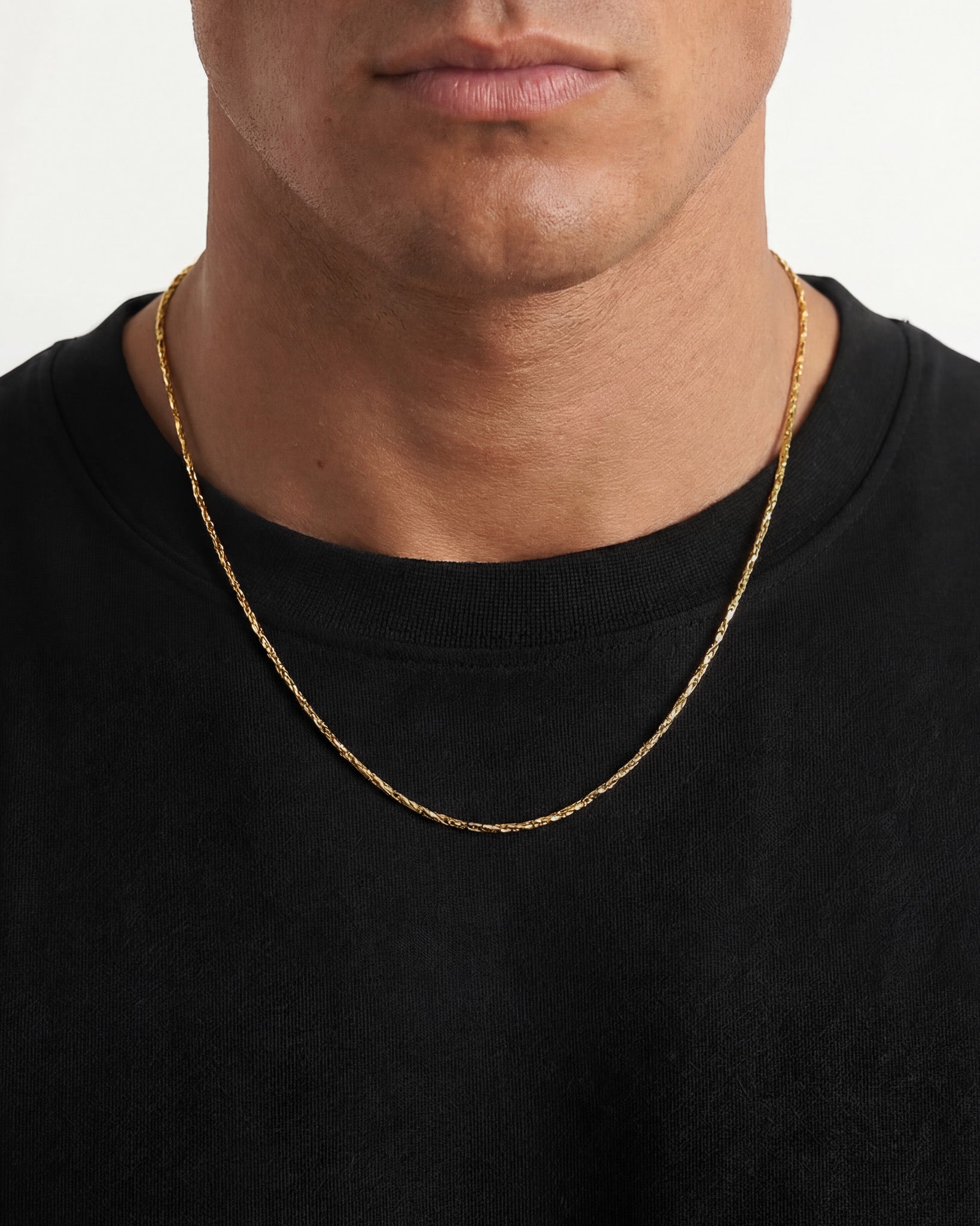 Person wearing the LIRA gold chain around the neck over a black shirt